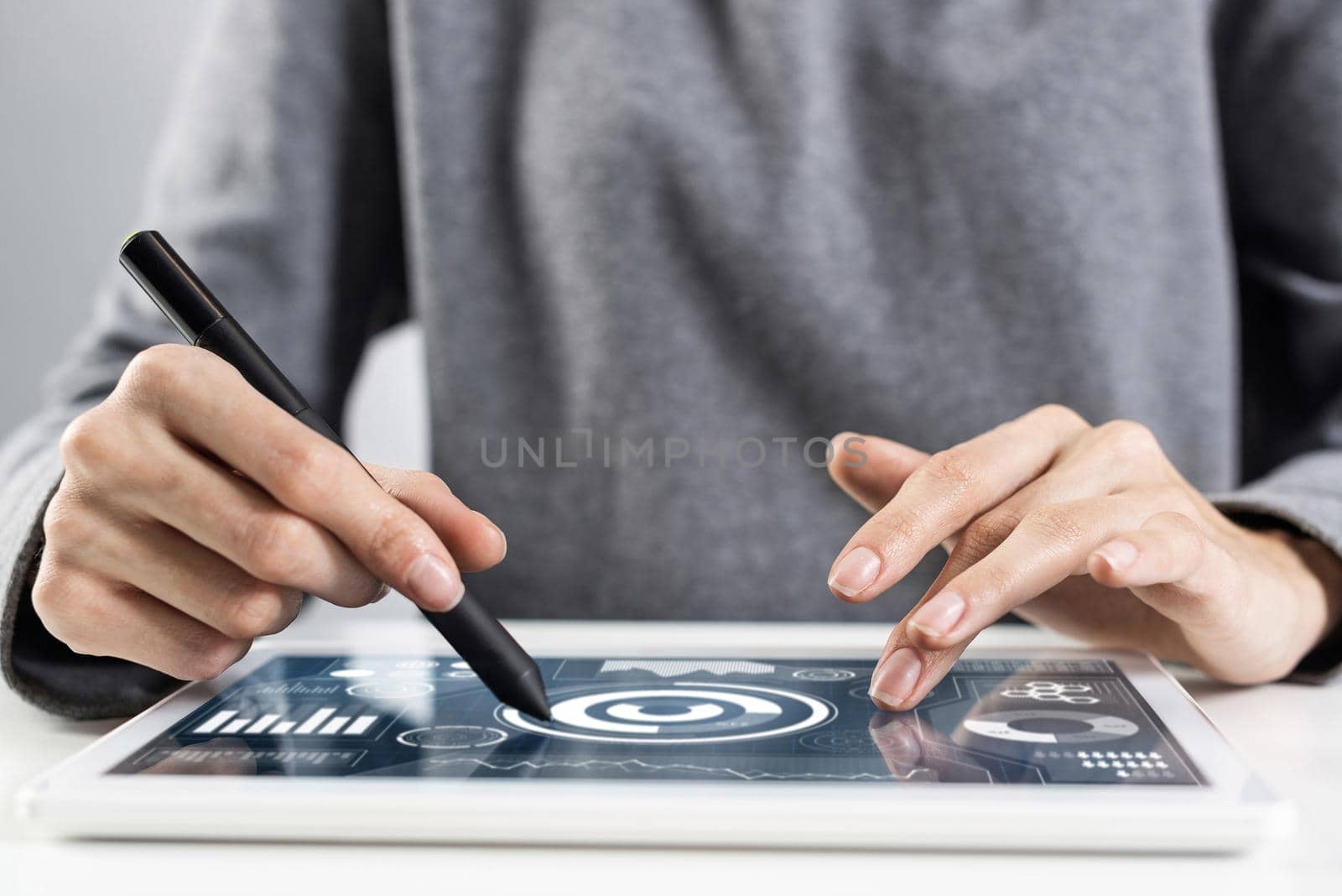 Woman using tablet computer for project management. Close-up of female hand holding pen and touching screen of tablet device. Online stock trading and investing. Mobile smart device in business