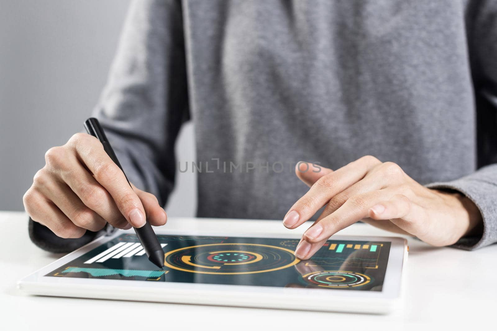 Woman using tablet computer for financial data analysis. Close-up of female hand holding pen and touching screen of tablet device. Online stock trading application. Mobile smart device in business