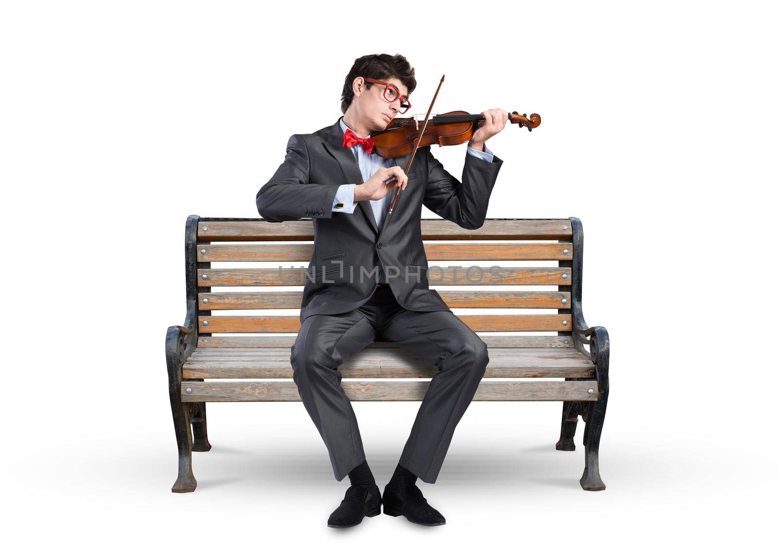 Young businessman plays the violin sitting on a wooden bench. Inspiration in business