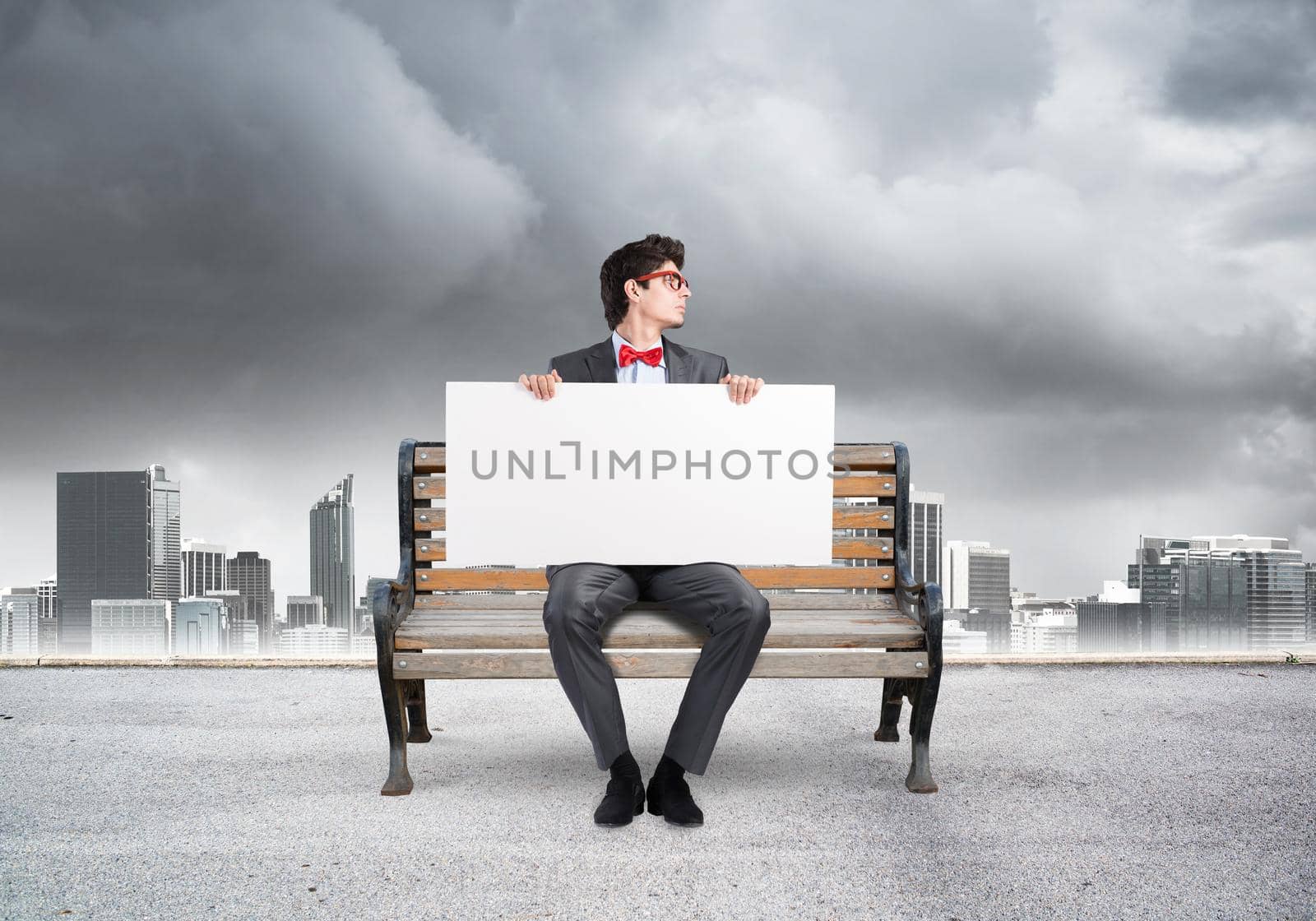 Young businessman holds a large white banner. sits on the bench