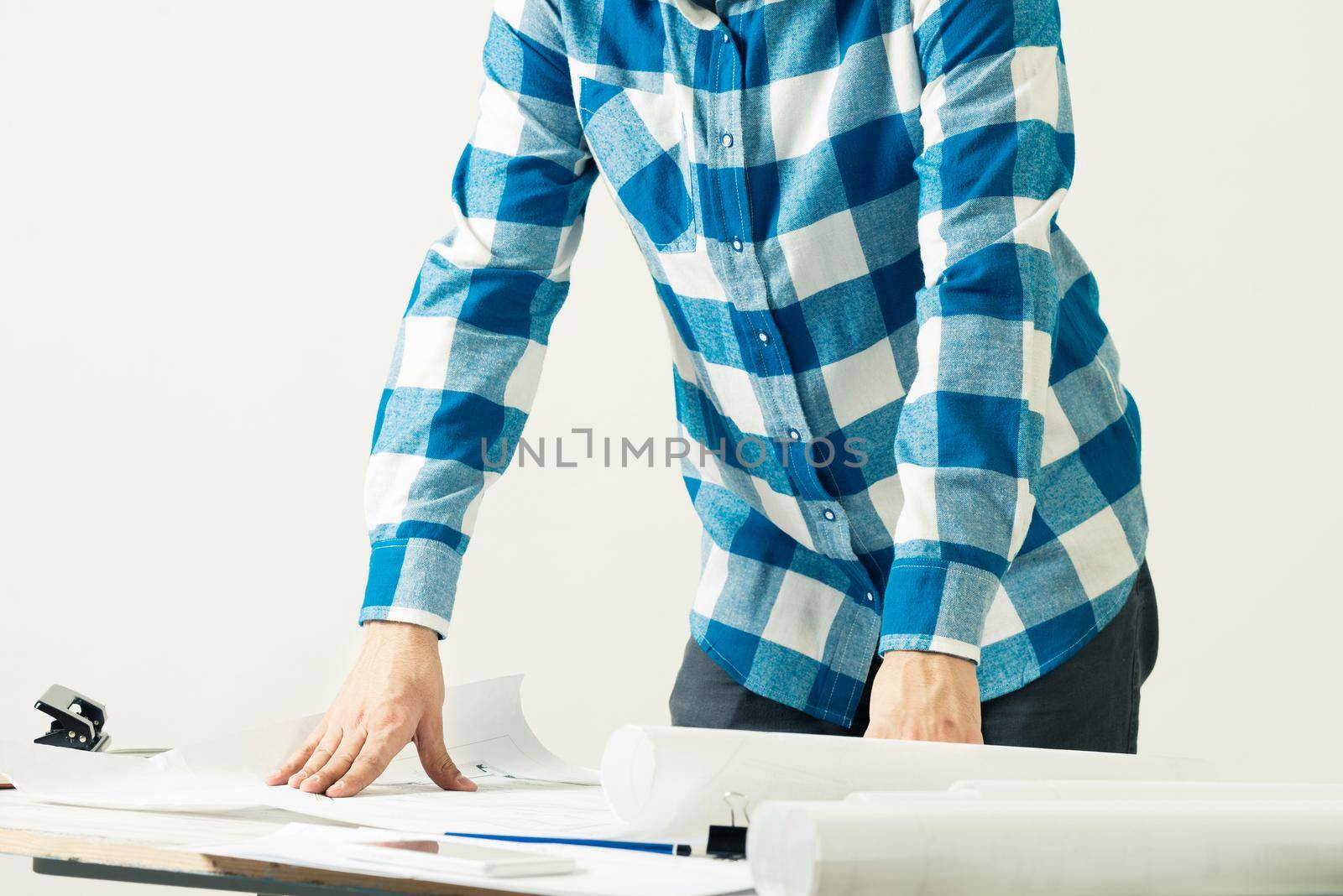 Architect standing near desk with paper blueprints by adam121