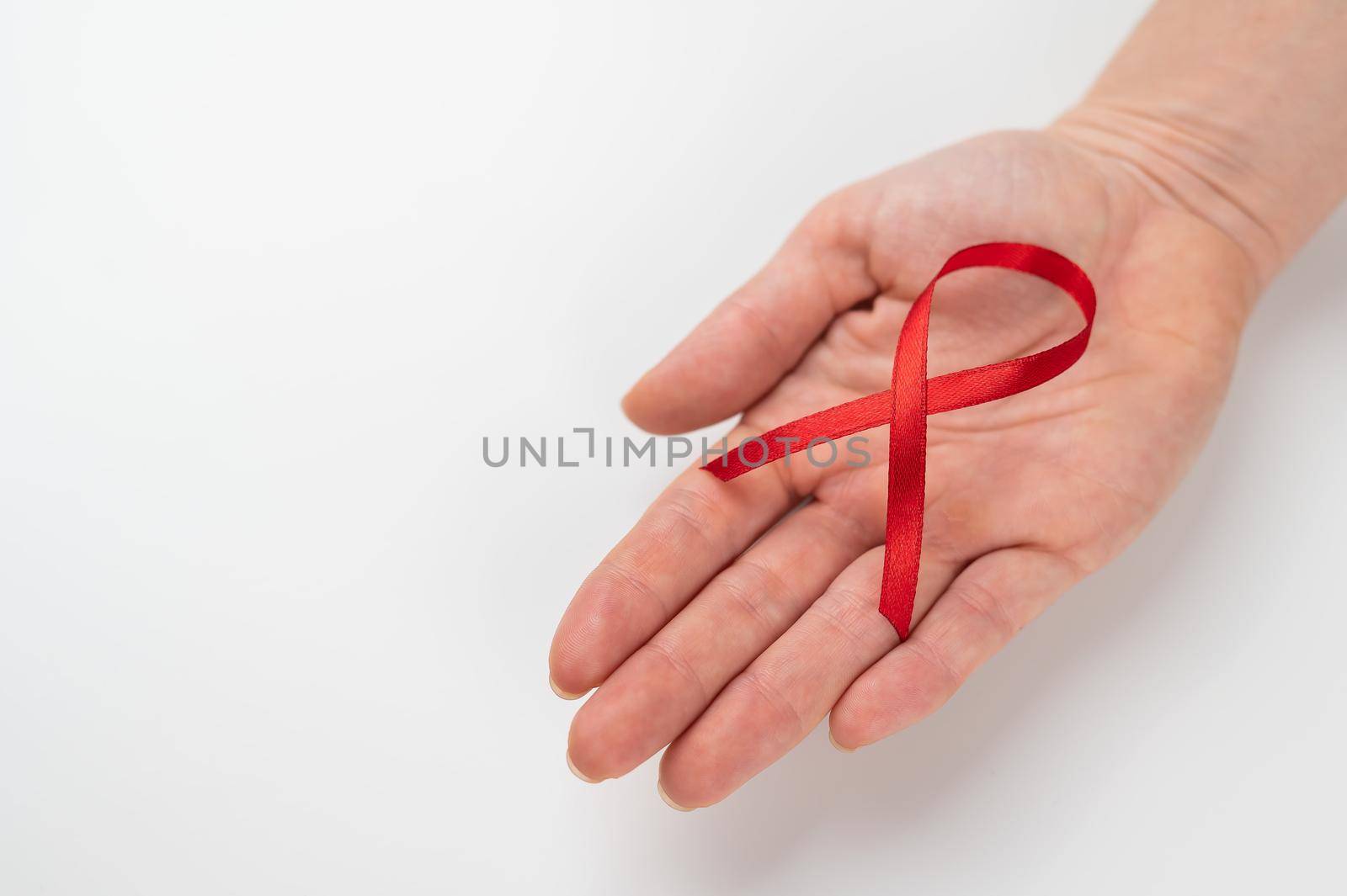 Female palm with a red ribbon on a white background. Symbol of the fight against AIDS. by mrwed54