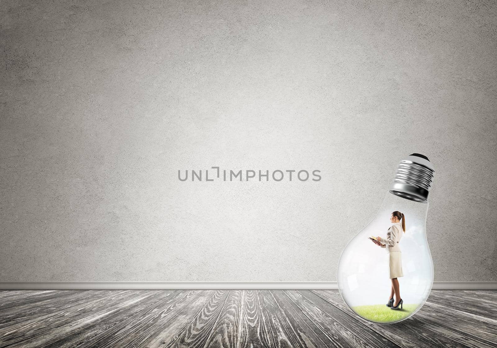 Businesswoman inside of light bulb in empty concrete room