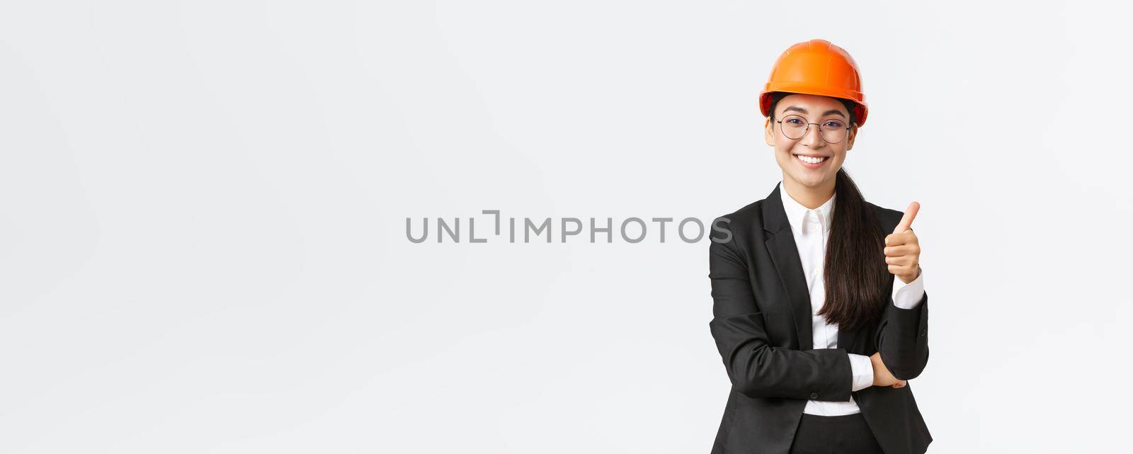 Satisfied female asian entrepreneur inspect enterprise, being pleased with construction work, showing thumbs-up in approval, smiling delighted, say well done, good job, guarantee finish build in time.