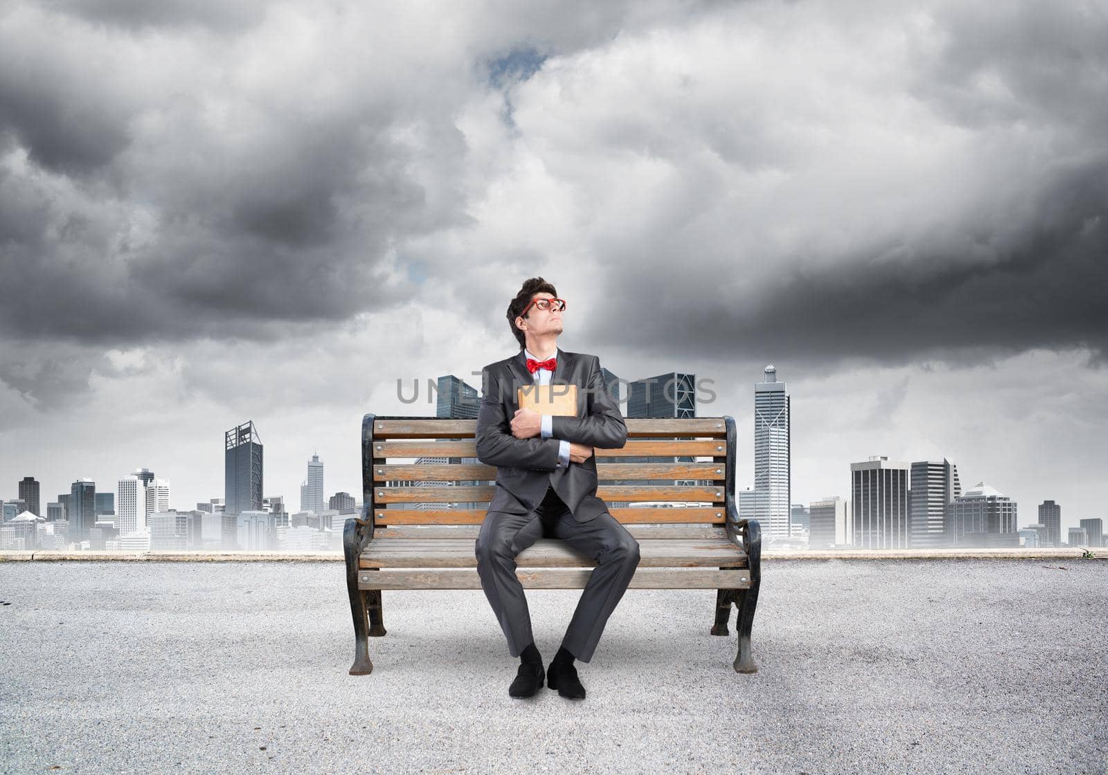 Student sits on a bench, holding a book. Traditional education concept