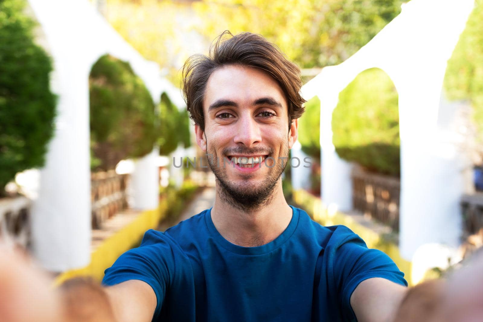 Front view of young man taking selfie holding the camera outdoors in city park. Lifestyle and social media concept.