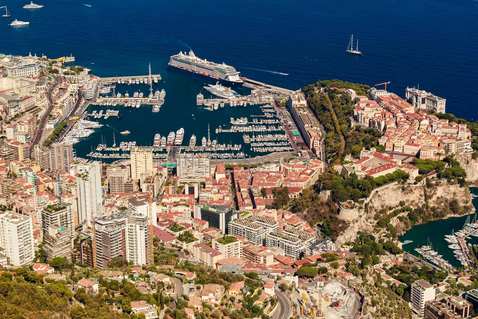 Aerial view of port Hercules of Monaco at sunset, Monte-Carlo, huge cruise ship is moored in marina, view of city life from La Turbie mountain, a lot of mega yachts and boats. High quality photo