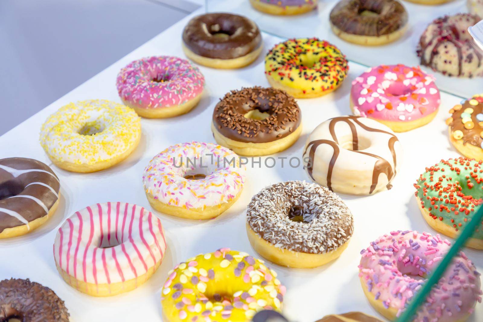 Different donuts are on display in a pastry shop by Milanchikov