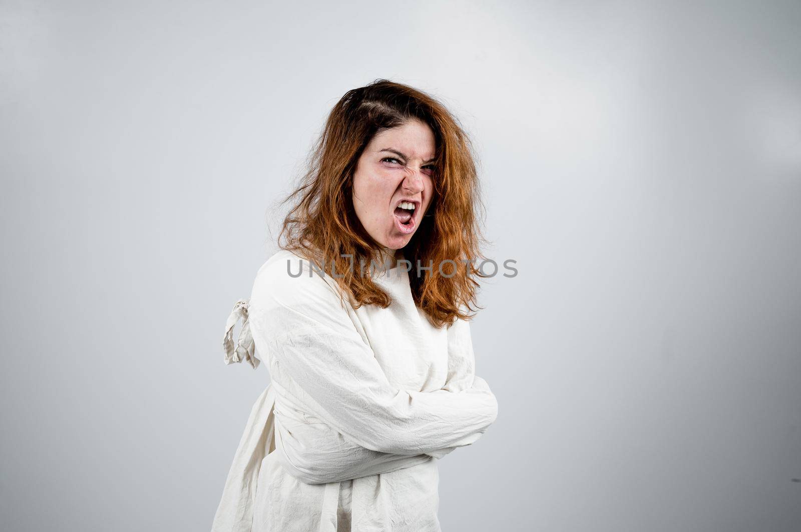 Close-up portrait of insane woman in straitjacket on white background. Monochrome. by mrwed54