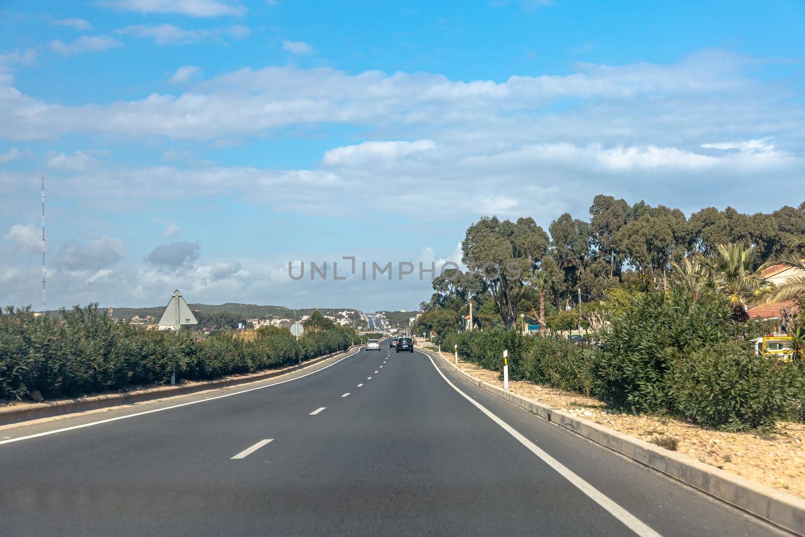 An empty highway through the hills. The city and the mountains are visible on the horizon.