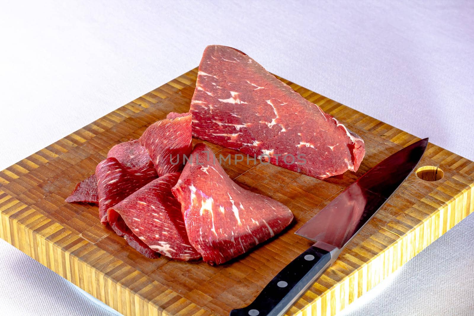 Roast beef. Thin slices of raw marbled beef lie on the board.