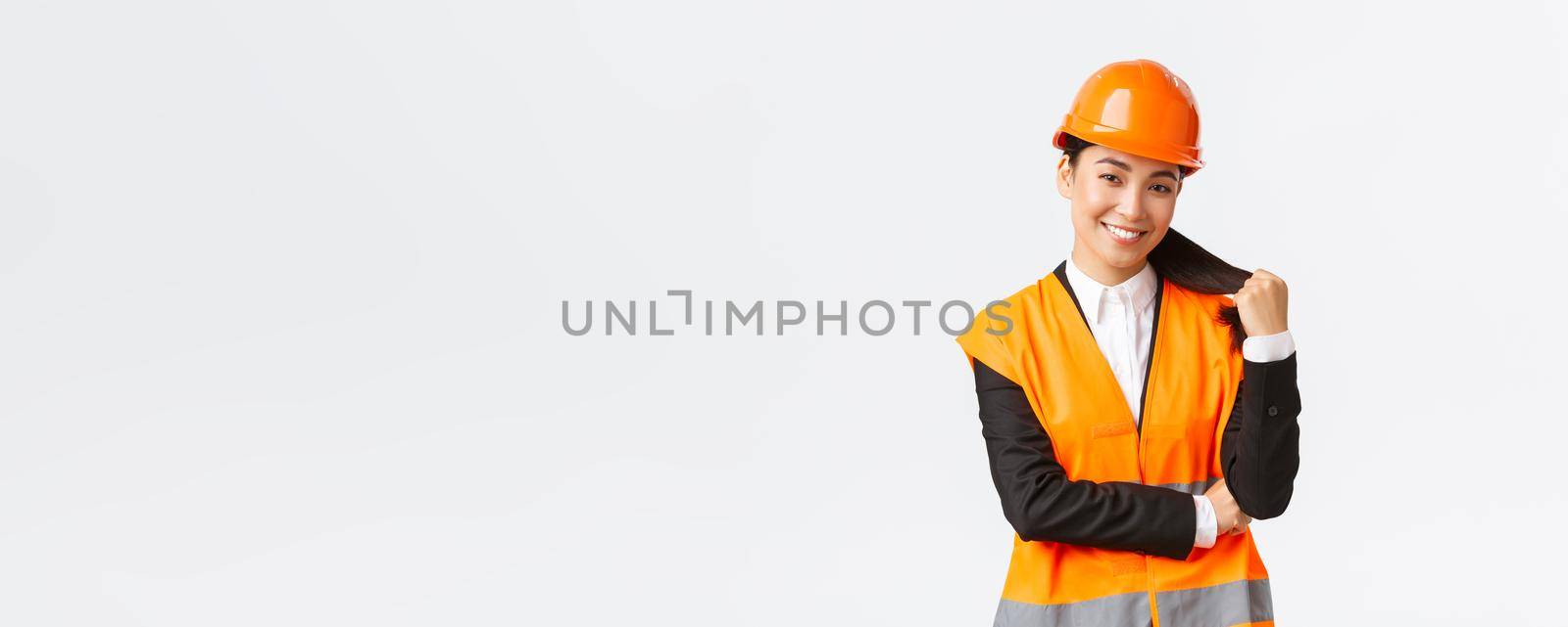 Portrait of confident smiling asian female construction manager, engineer at building area, wearing safety helmet and reflective jacket looking delighted at project, being pleased with finished work by Benzoix