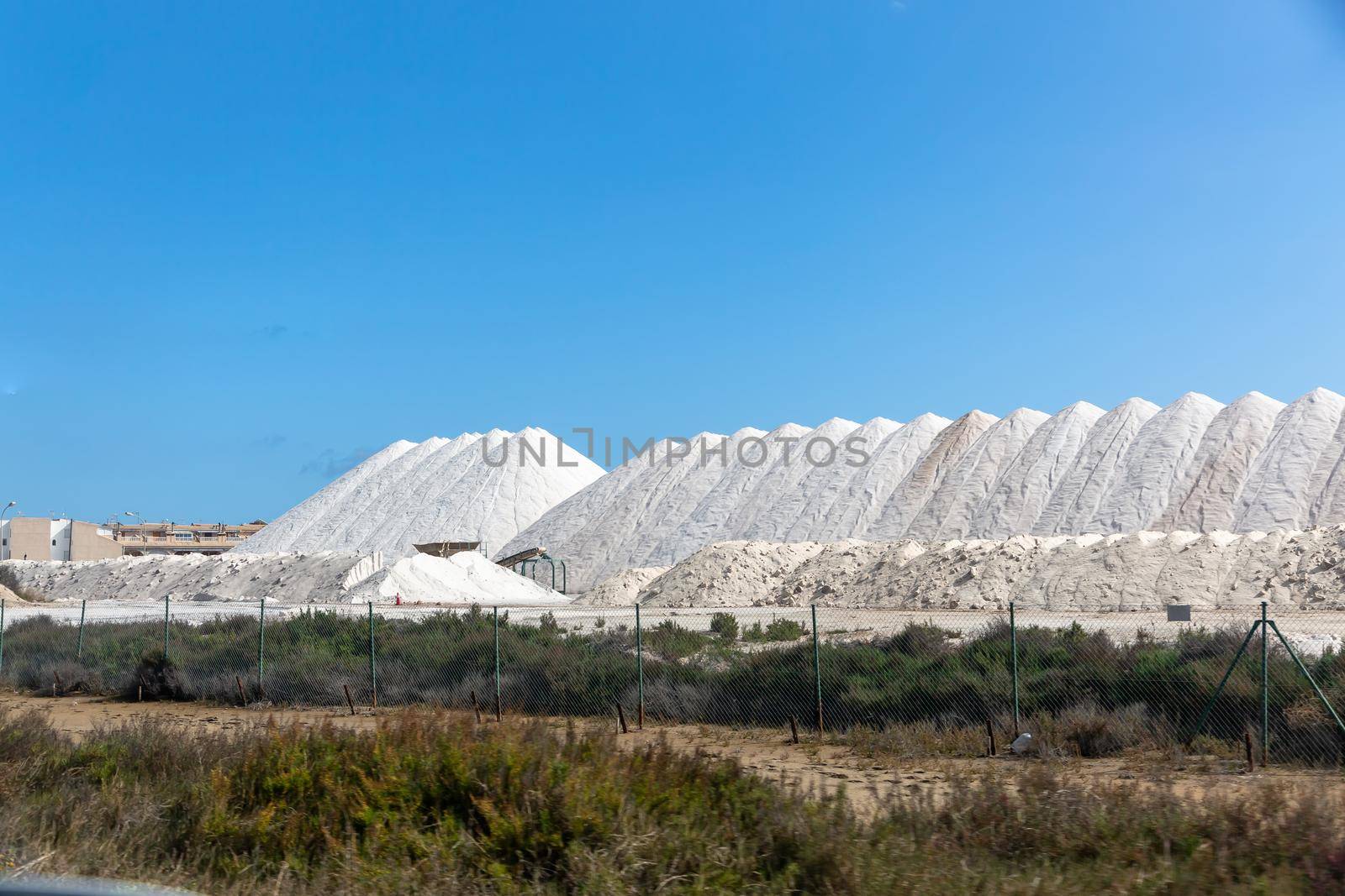Sea salt in the warehouse in the form of large hills. Salt production plant, Mediterranean by Milanchikov
