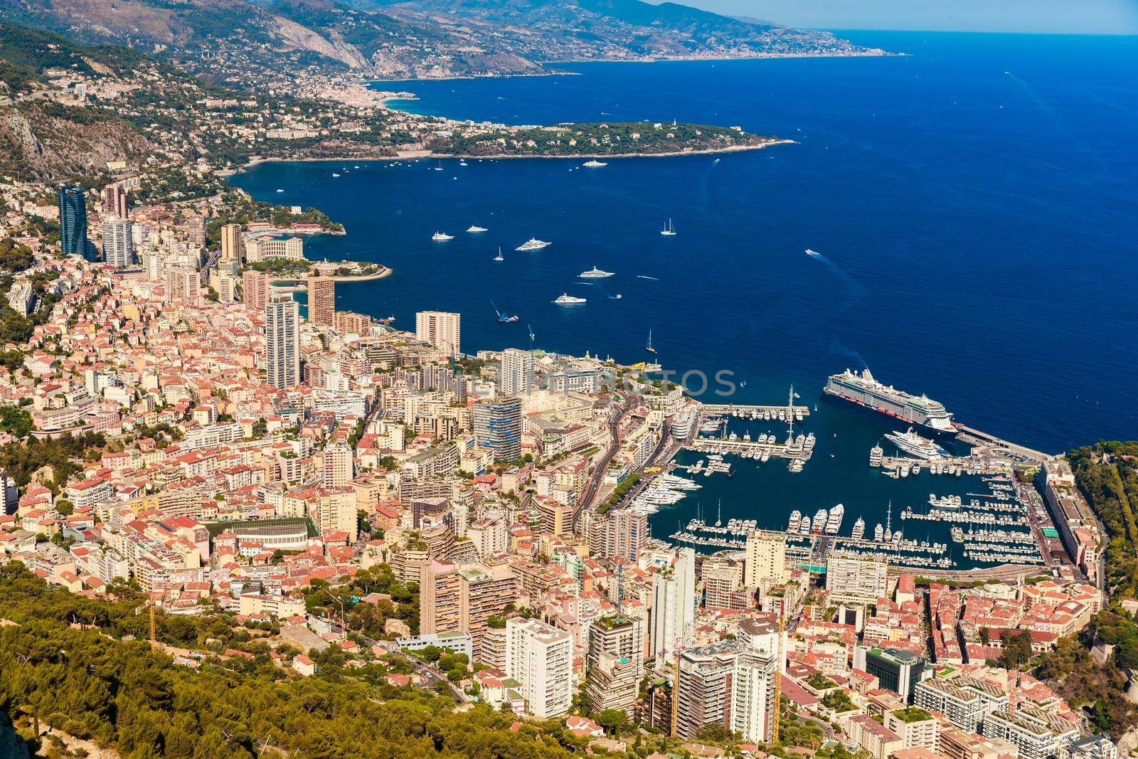 Aerial view of port Hercules of Monaco at sunset, Monte-Carlo, huge cruise ship is moored in marina, view of city life from La Turbie mountain, a lot of mega yachts and boats. High quality photo