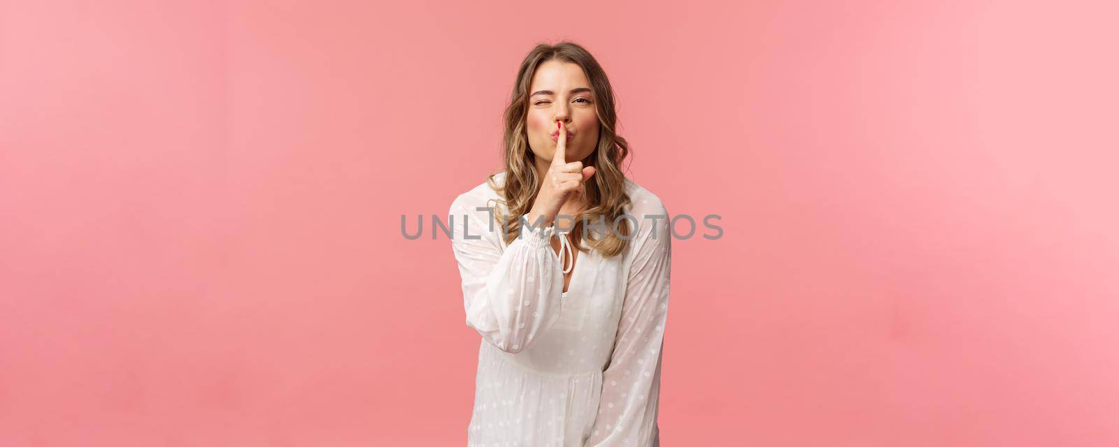 Beauty, fashion and women concept. Portrait of feminine and flirty caucasian woman hiding secret, asking keep silent, shushing with sensual coquettish smile, wear white dress, pink background by Benzoix