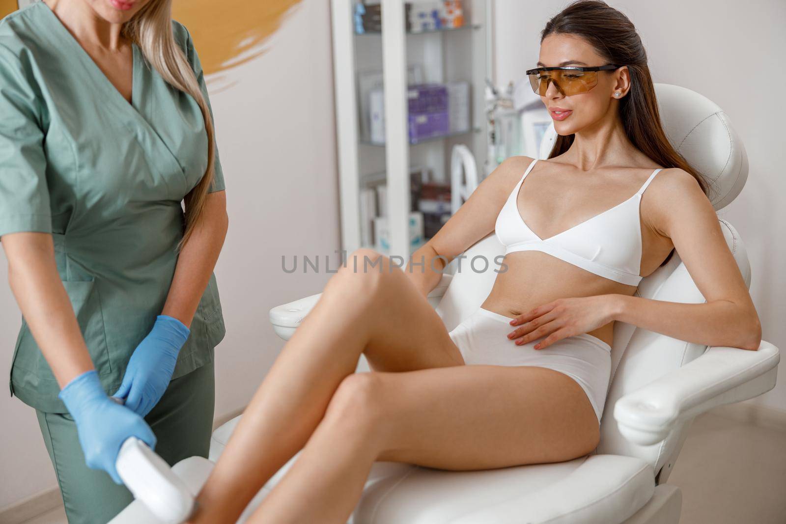 Young woman in underwear and protective glasses during laser epilation procedure in beauty salon by Yaroslav_astakhov