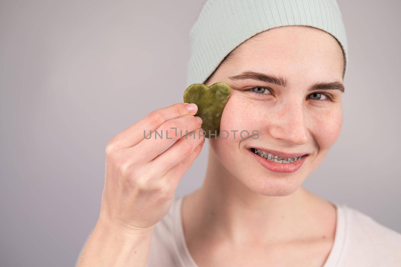 Close-up portrait of a smiling woman with braces doing home care with a gouache massager