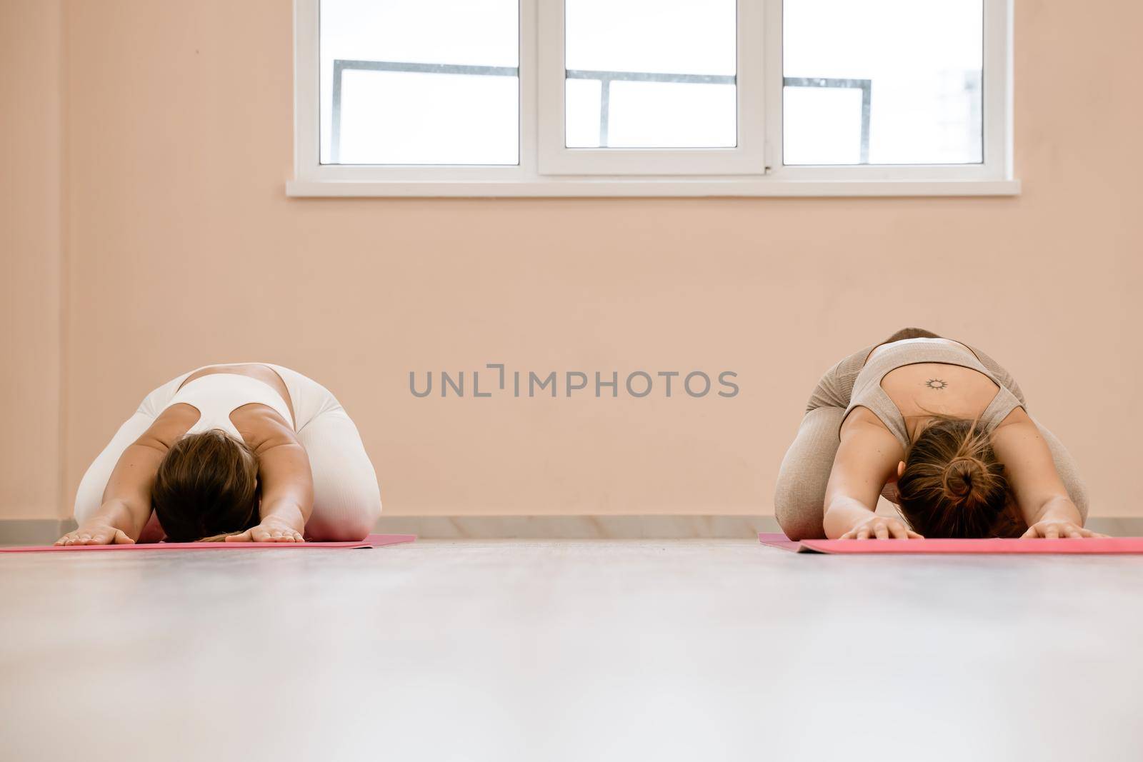 Two beautiful women do yoga, sports in the gym. The concept of grace and beauty of the body