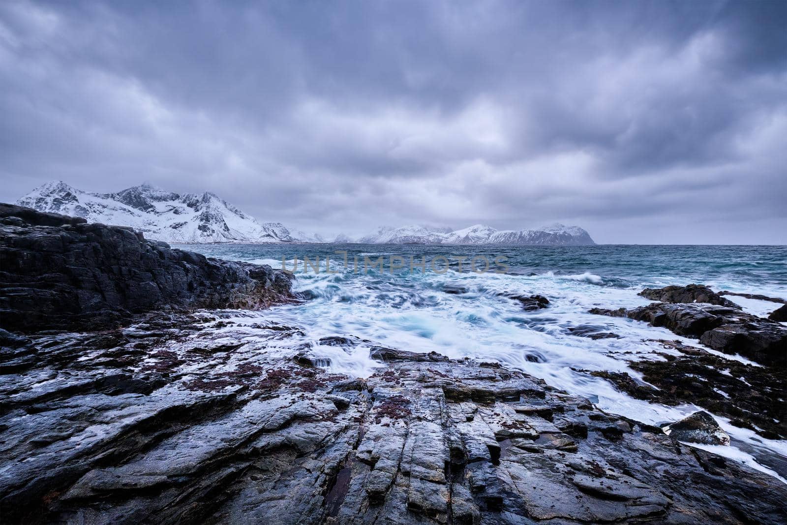 Waves of Norwegian sea crushing at rocky coast in fjord. Vikten, Lofoten islands, Norway