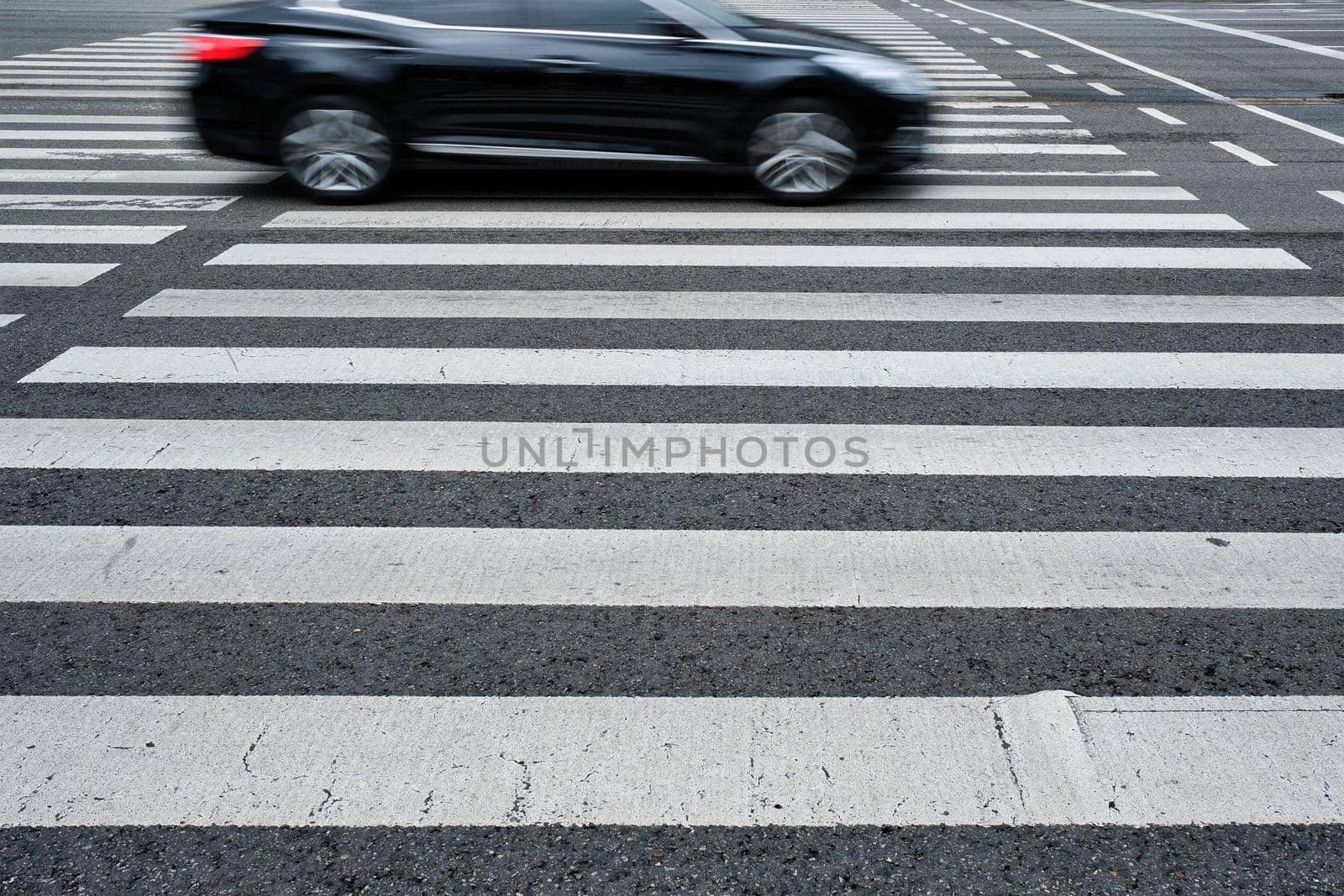 Crosswalk pedestrian crossing with blurred car on asphalt road in the street