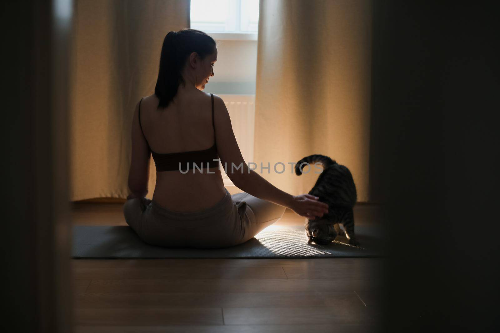 Young woman practices yoga and meditation at home with her cat. Doing exercises at home. Meditation and mental health concept