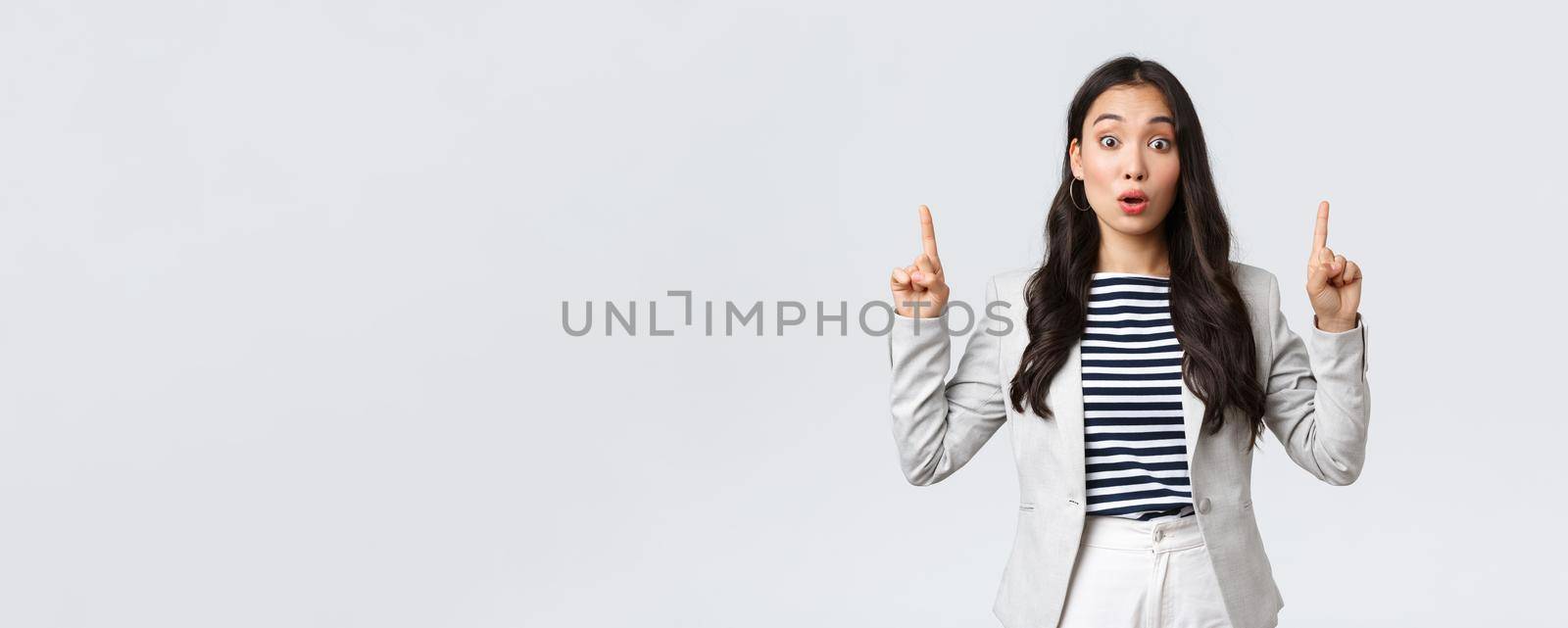 Business, finance and employment, female successful entrepreneurs concept. Real estate worker in white suit inform people about special offer, pointing fingers up saying wow.