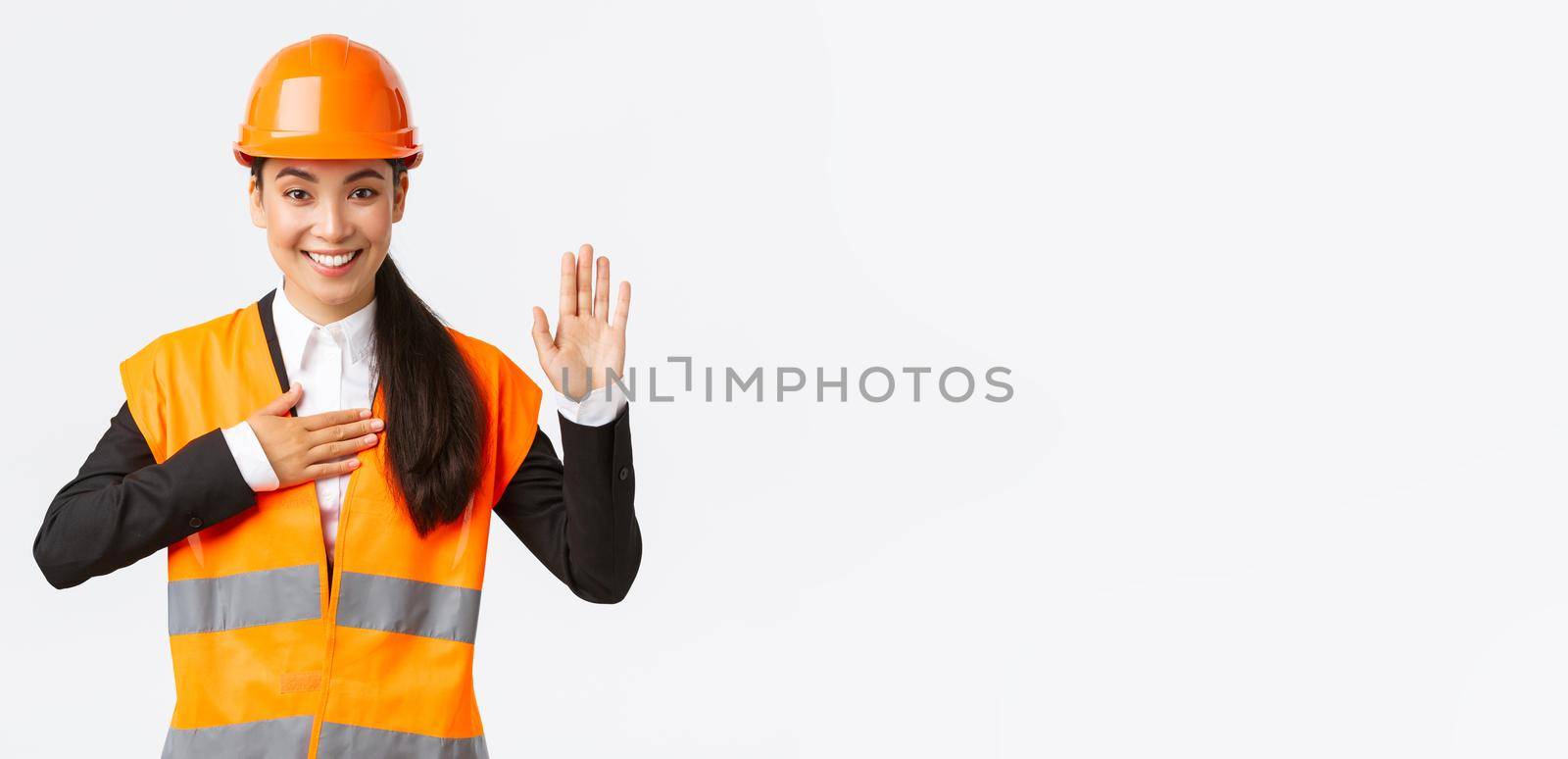 Sincere, honest and confident asian female engineer at building area, making promise, give oath to clients, looking trustworthy, standing in safety helmet, telling truth, white background.