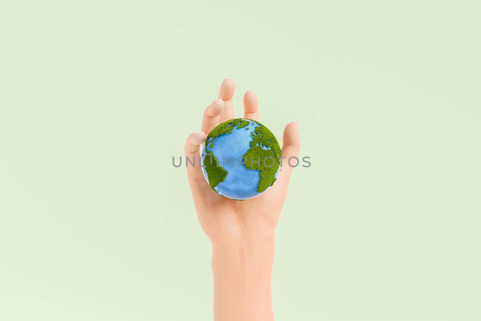 Hand of person holding small planet Earth covered with green moss and blue oceans on clear light background in studio. 3d rendering