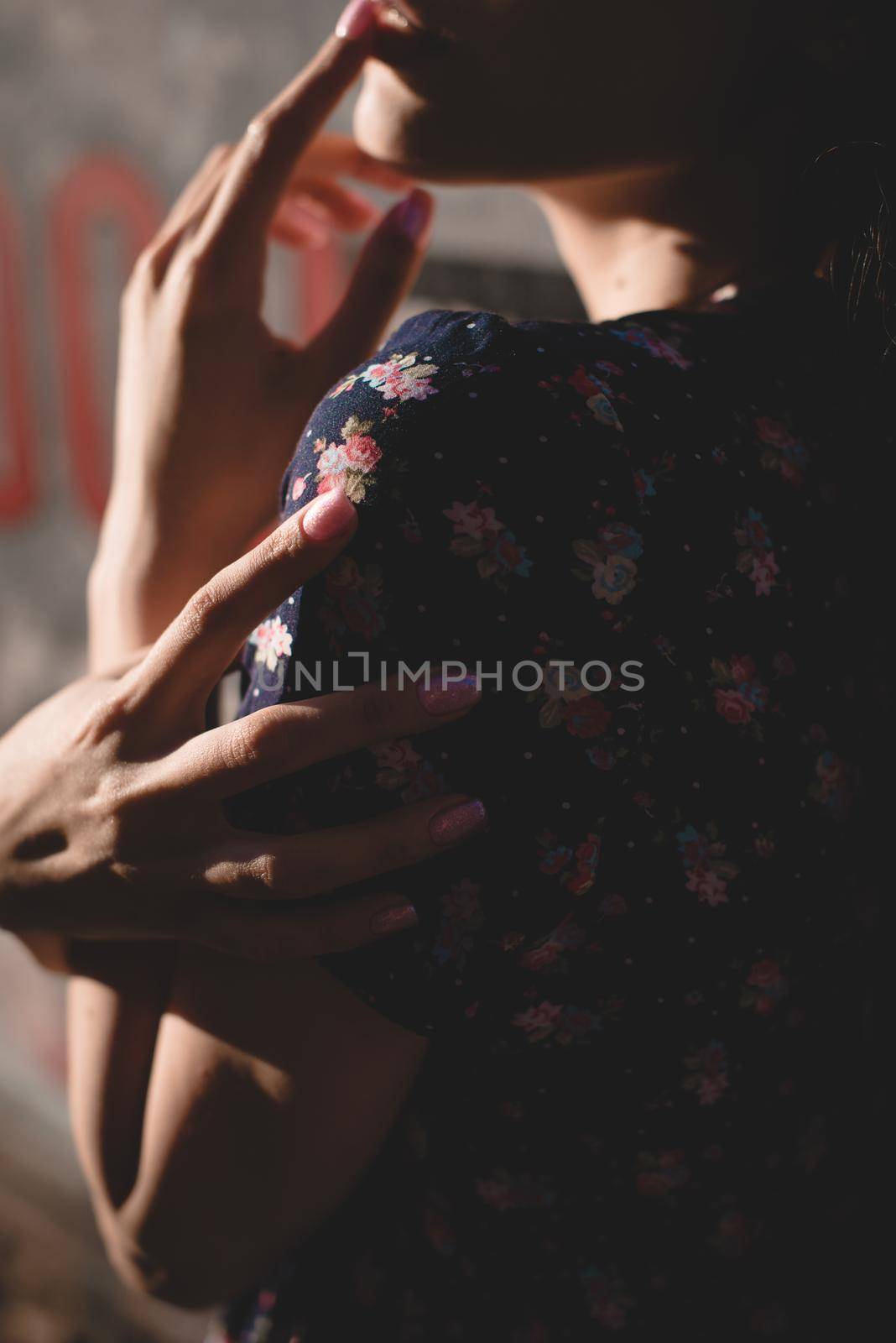 Close-up portrait of stylish young woman. Brunette in sundress posing on street. Finger near her lips