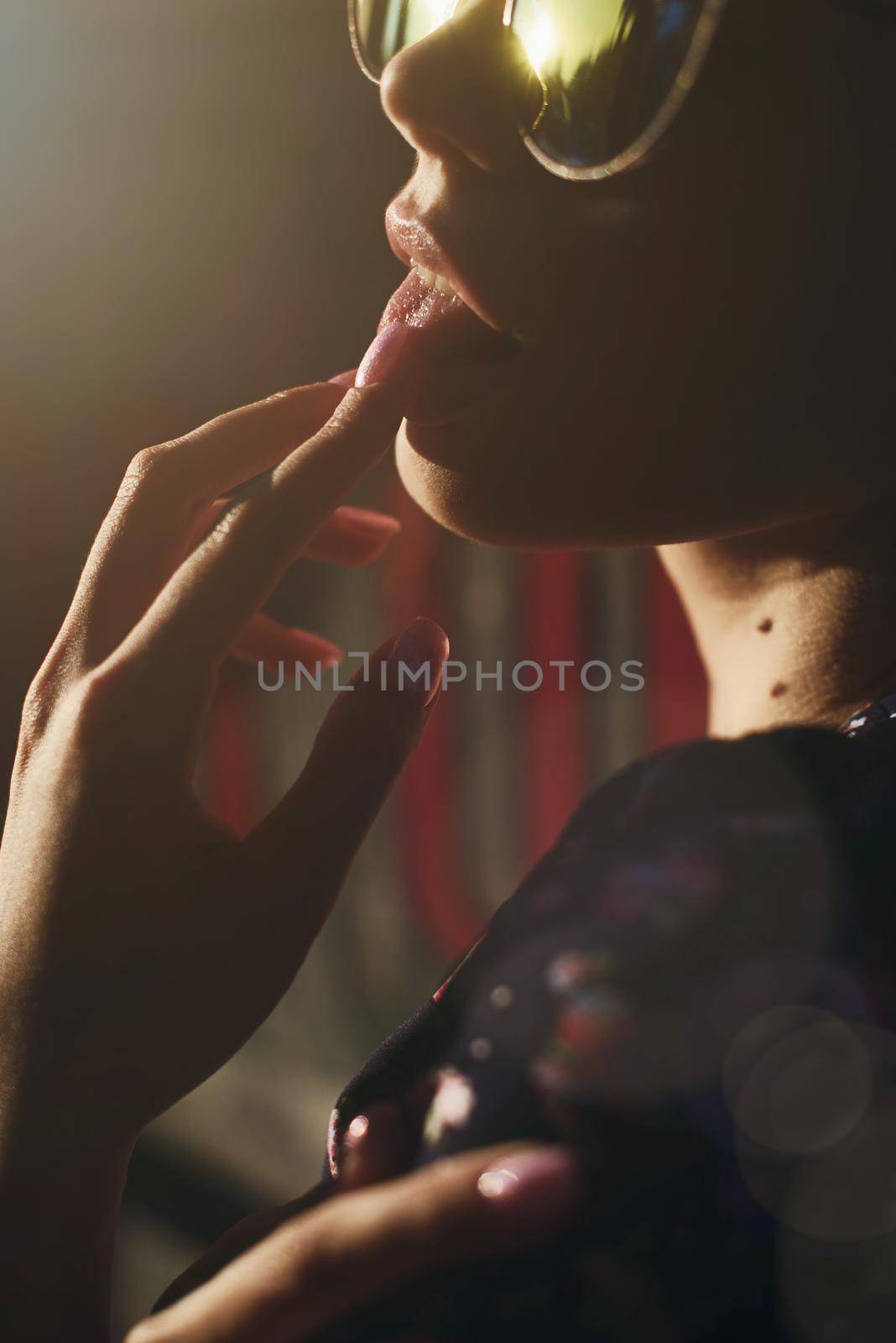 Close-up portrait of stylish young woman. Brunette in sundress posing on street. Finger near her lips