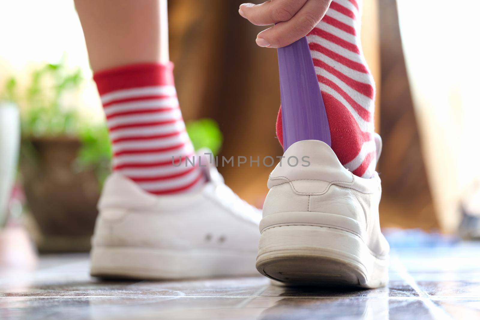 Person puts a shoehorn into sneakers closeup by kuprevich