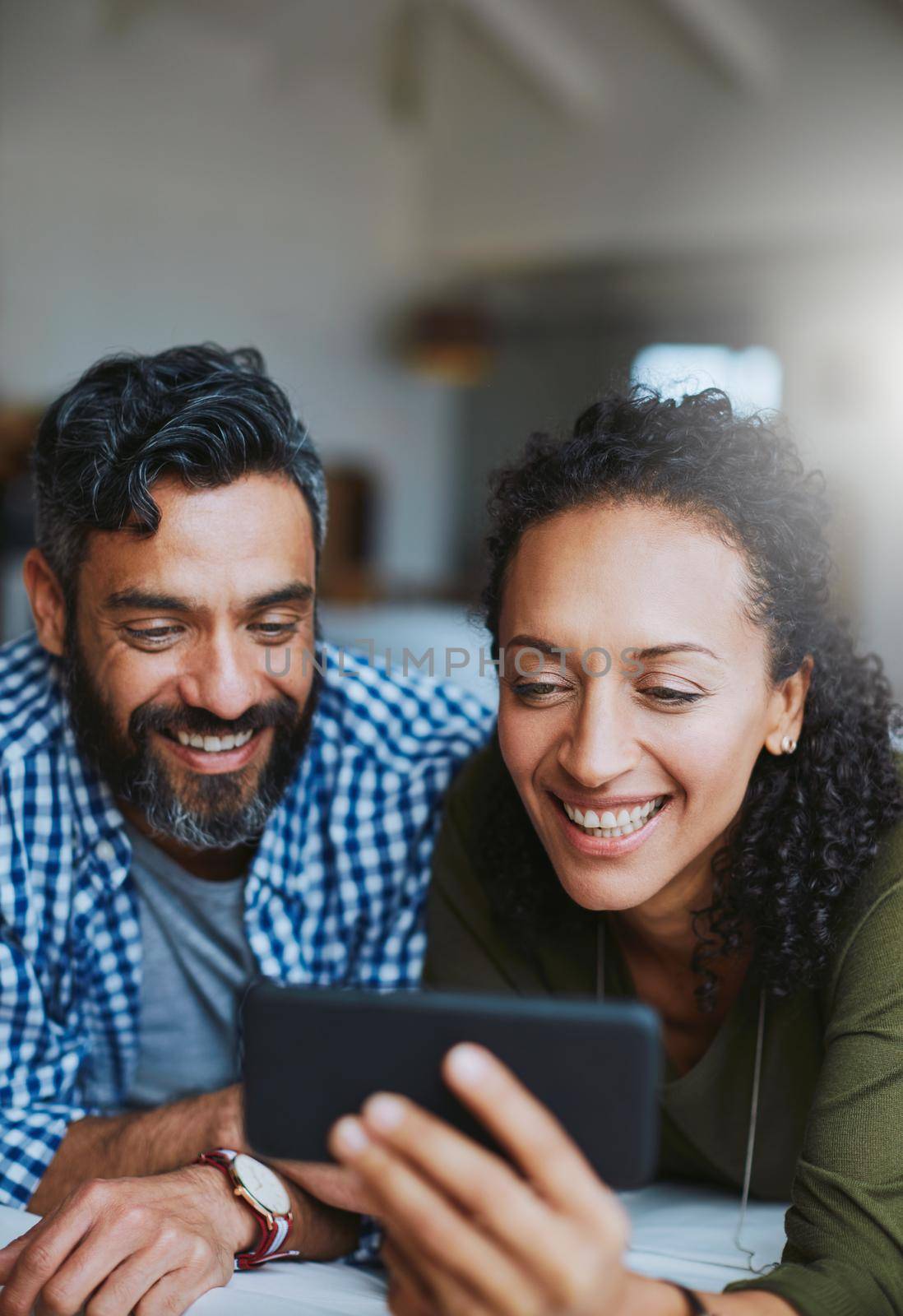 Putting the social back in social media. Shot of a laid-back couple relaxing with wireless technology at home. by YuriArcurs