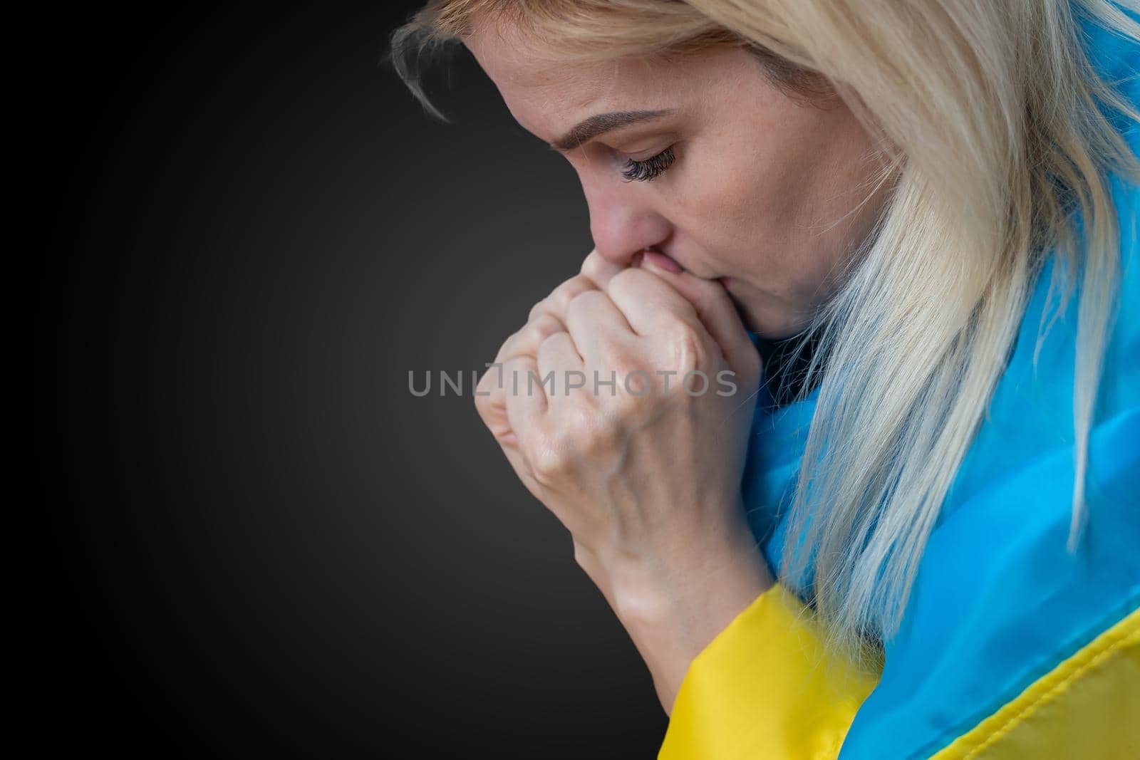 Beautiful young woman with flag of Ukraine on dark background, closeup.