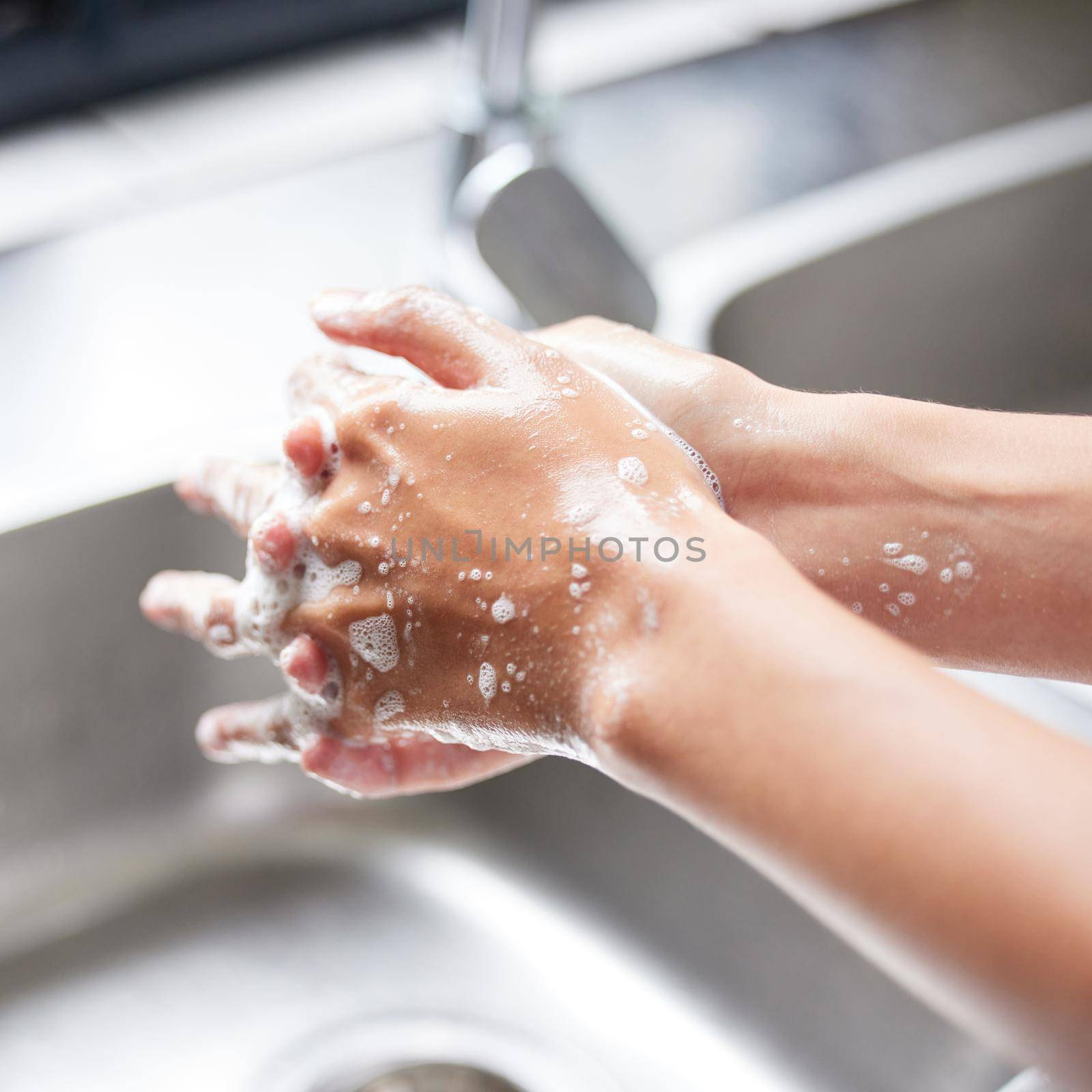 I wash my hands the minute I enter the house. Cropped shot of an unrecognizable woman washing her hands in the sink at home. by YuriArcurs