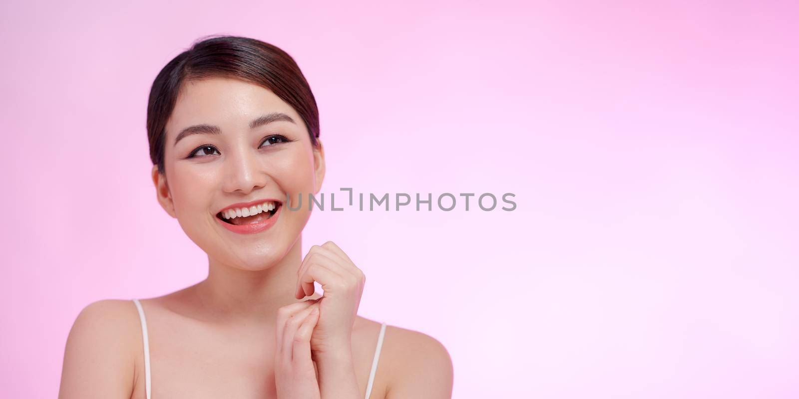 Woman close-up beauty portrait hands touching face on pink background