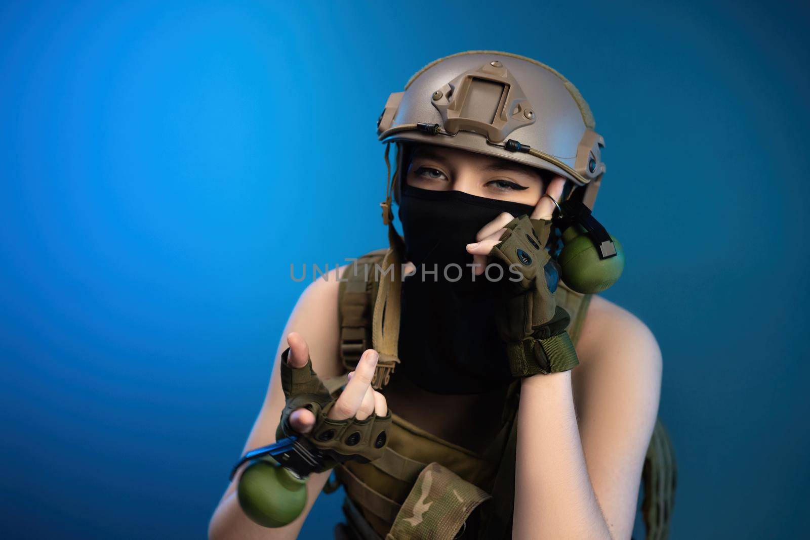 the sexy girl soldier in helmet and bulletproof vest in military clothes with grenades posing in the studio