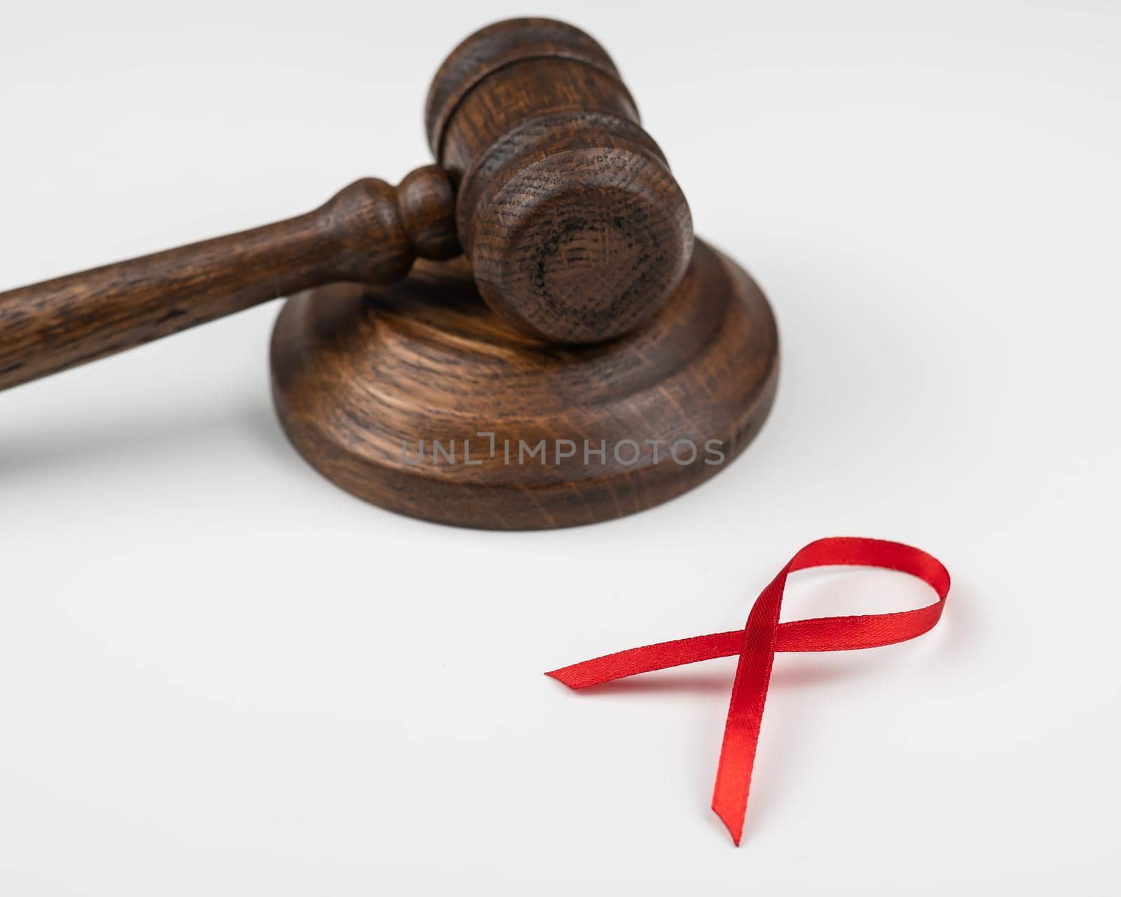 Judicial gavel and red ribbon on a white background. Symbol of the fight against AIDS