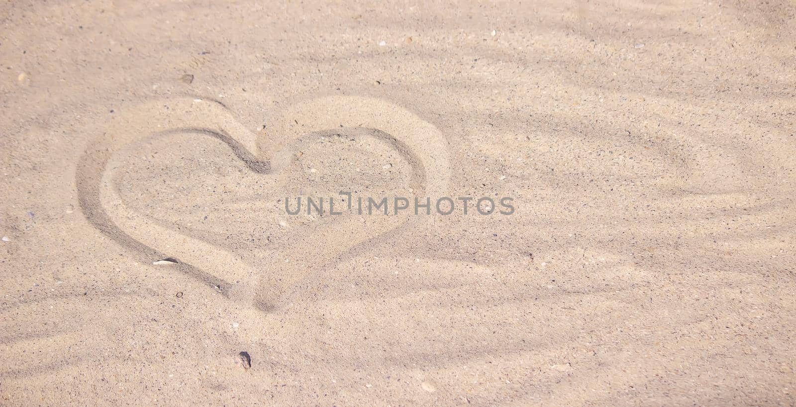 Heart drawn in the sand. Beach background. Top view. selective focus