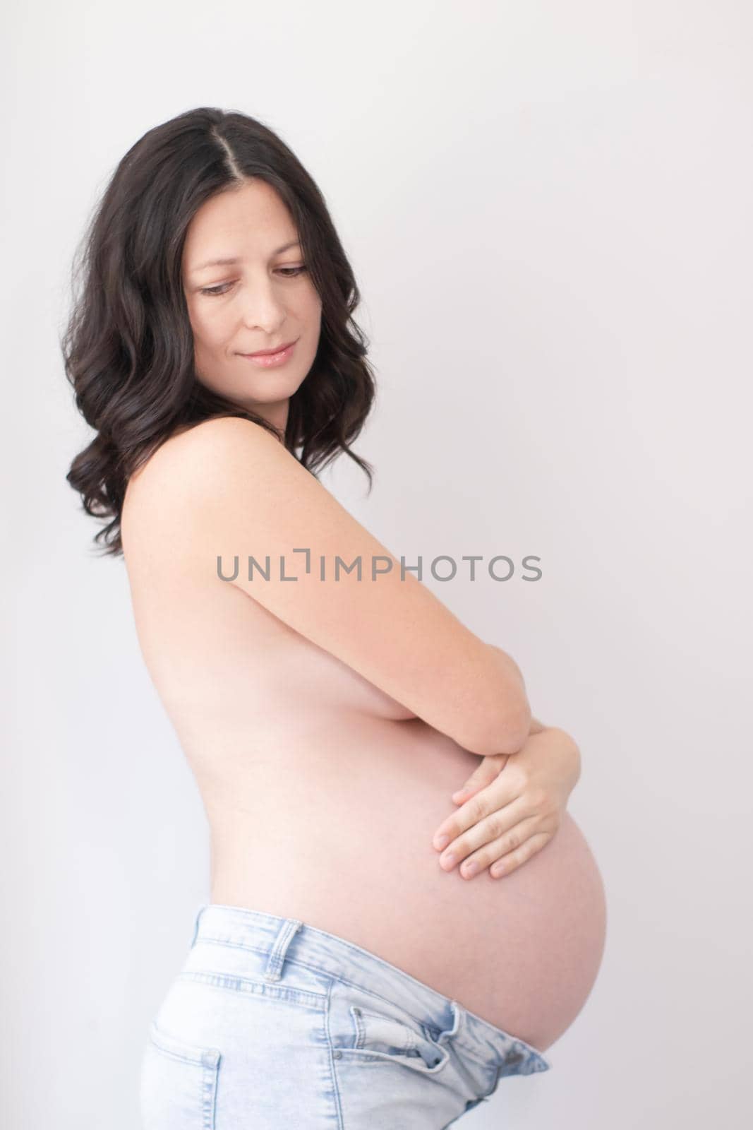 happy pretty woman enjoying pregnancy. mother to be is expecting parent. cute big tummy. pregnant brunette in light room by oliavesna