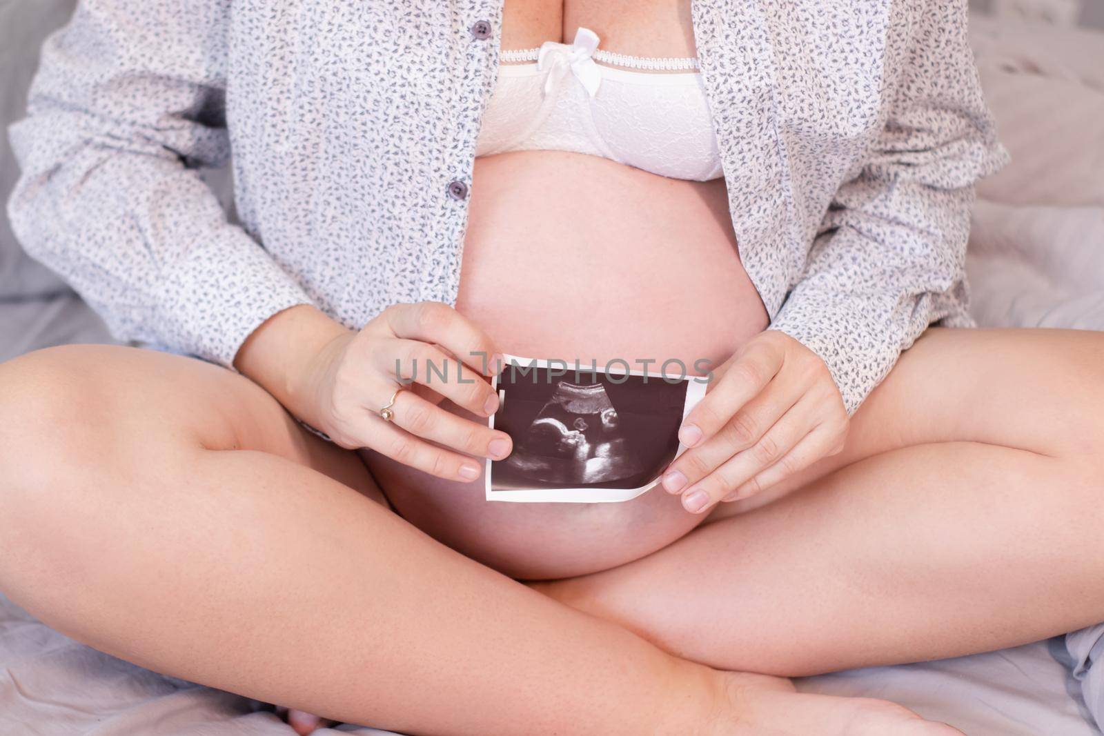 pregnant woman with a photo of ultrasound of pregnancy. enjoying pregnancy happy time. mother to be with cute big tummy.