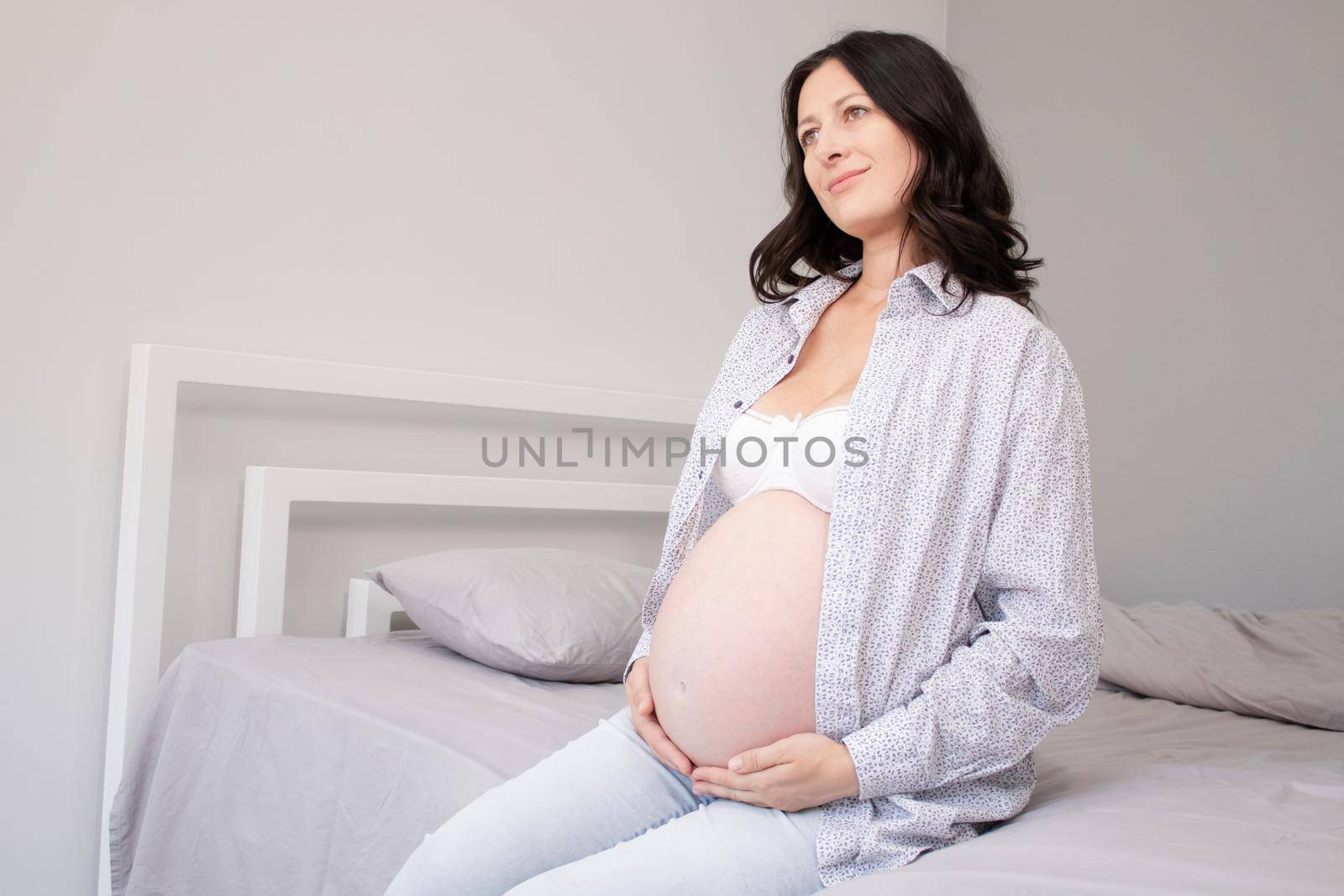 charming pregnant woman in shirt on bed. happy pregnancy.