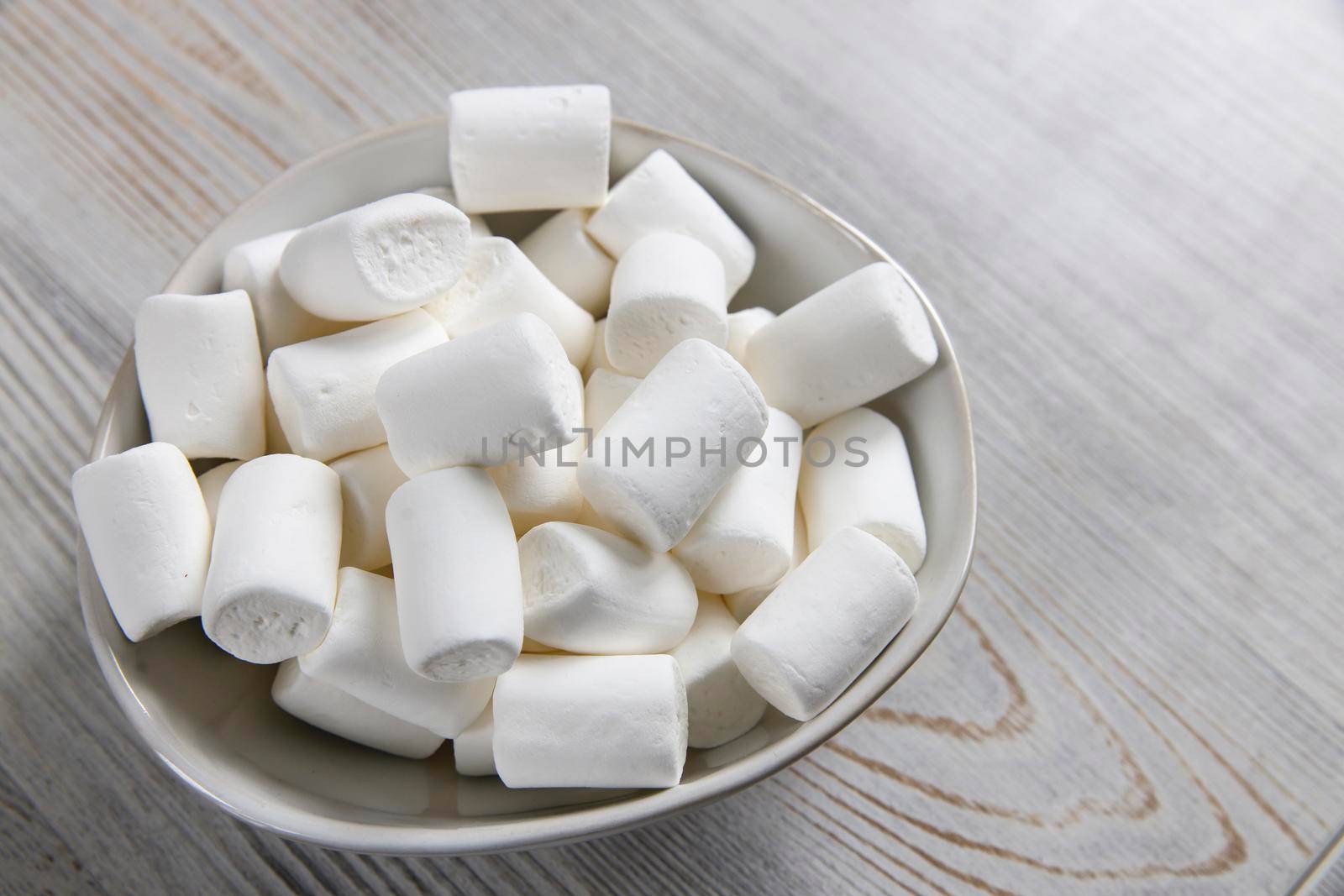 White marshmallows in a porcelain bowl on the table