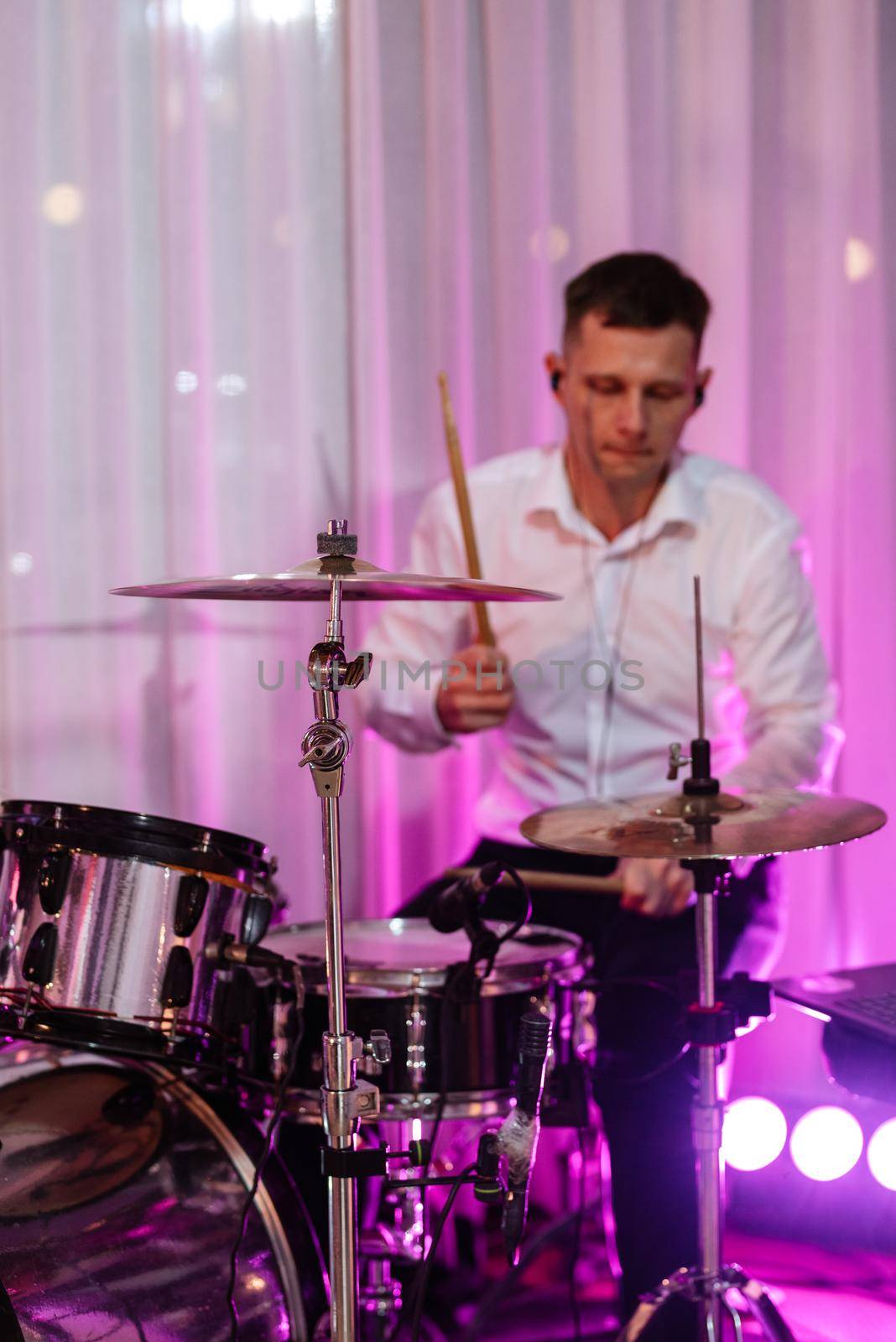 guy musician plays the drum at a concert in stage lighting