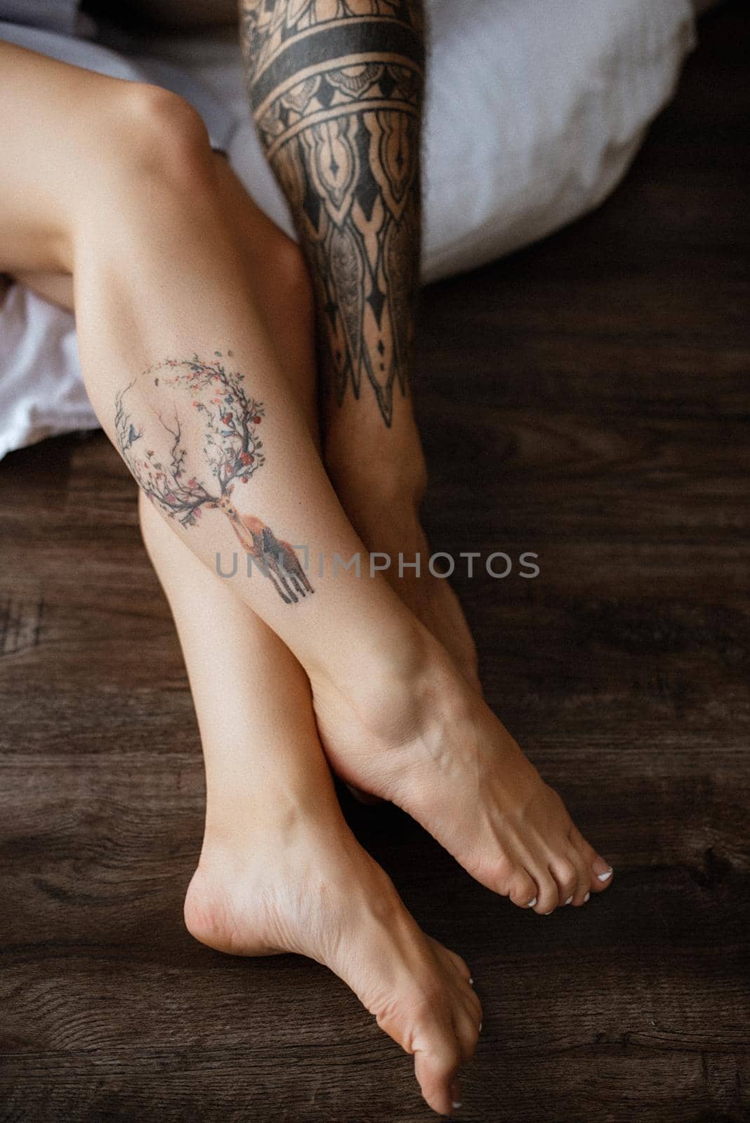 crossed legs of a guy and a girl with tattoos