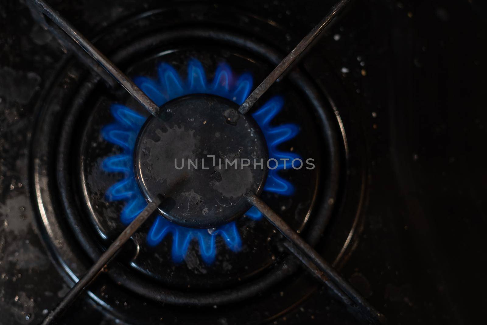 Closeup shot of blue fire from domestic kitchen stove top. Gas cooker with burning flames of propane gas. Industrial resources and economy concept. by Andelov13