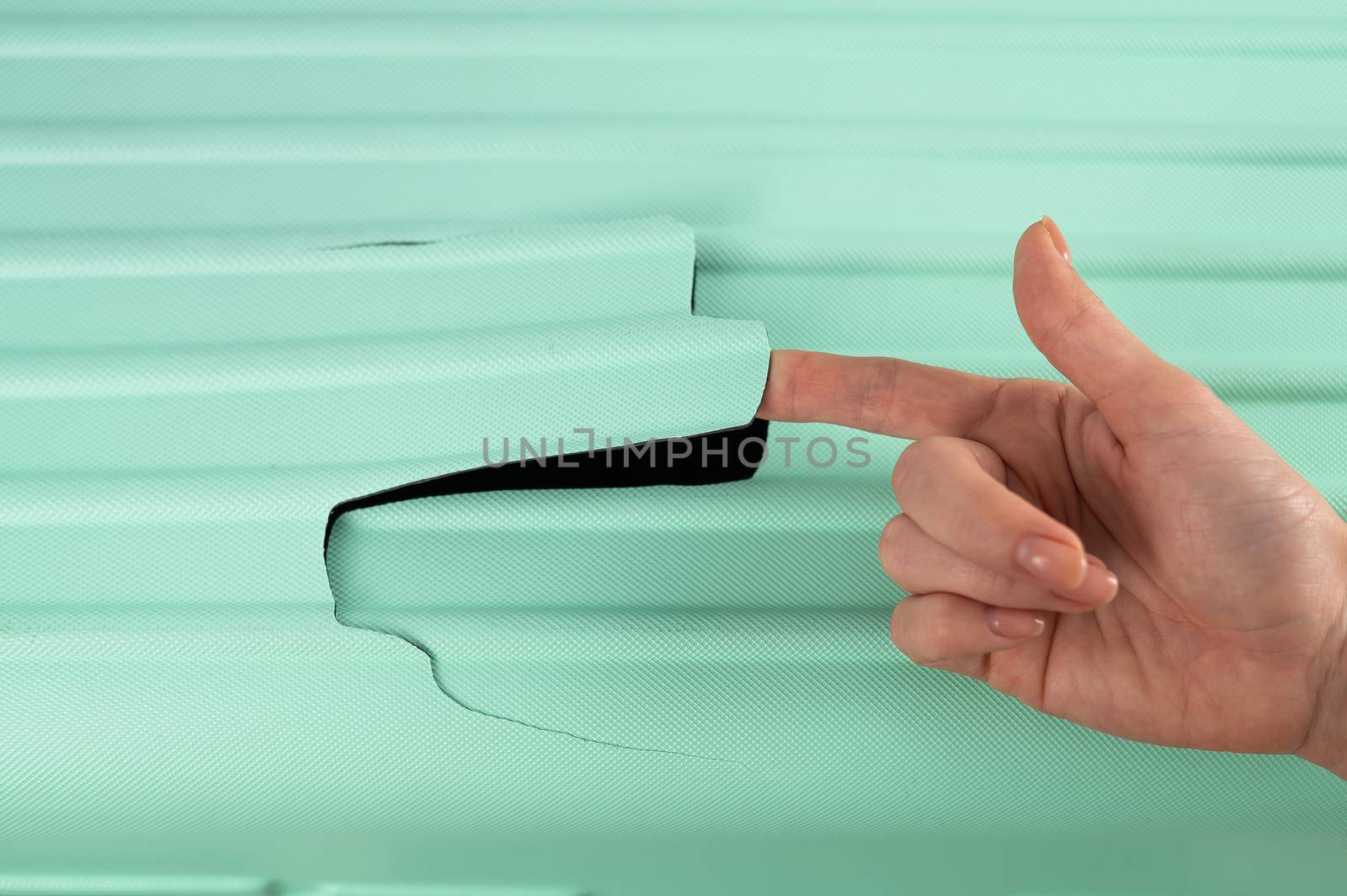 A woman demonstrates a broken suitcase on a white background. Damaged baggage during the flight