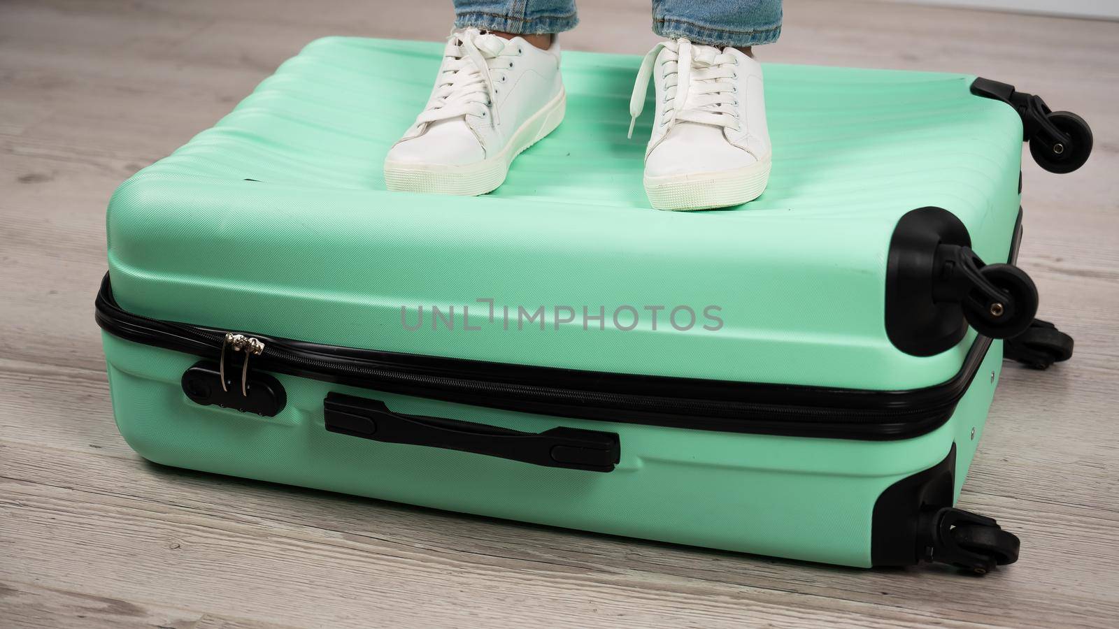 Woman standing with her feet on a suitcase