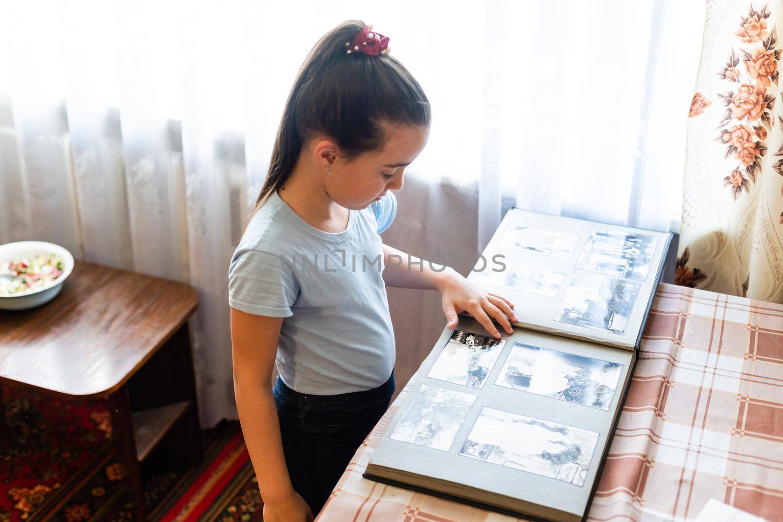 Adorable girl browsing an family album. Vintage style by Andelov13