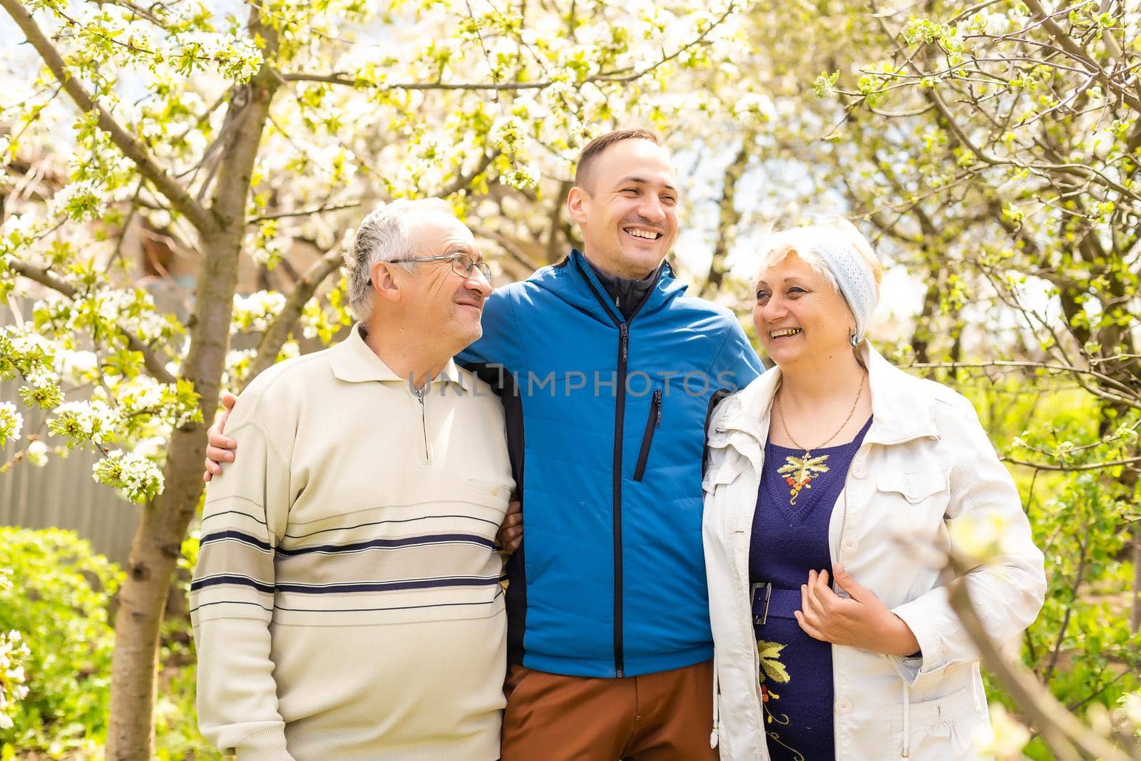 Adult son with his elderly parents outdoors in a natural setting