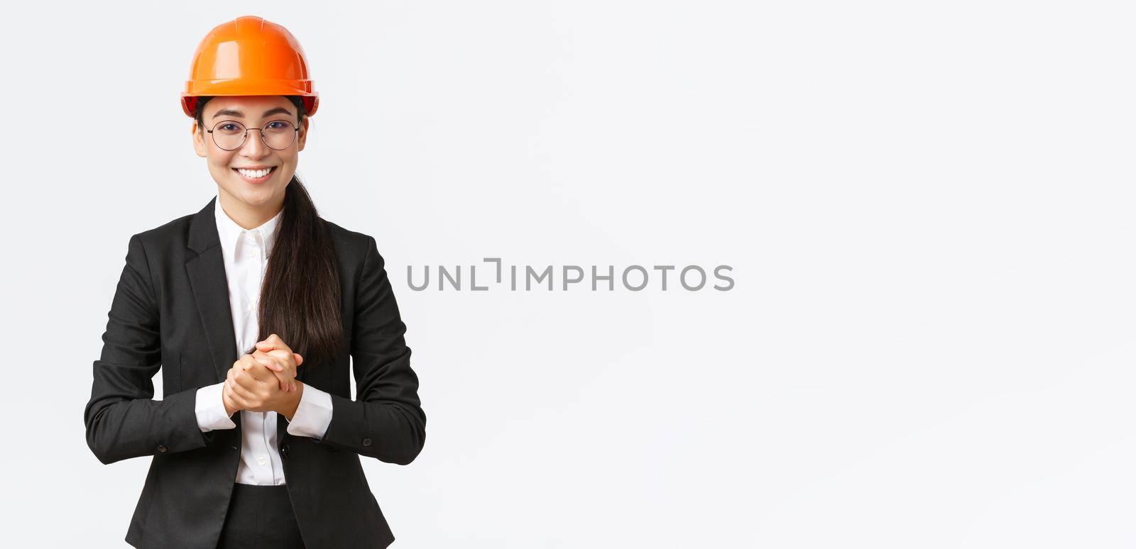 Smiling professional asian businesswoman in safety helmet and business suit introducing enterprise to clients or investors, showing around, making presentation at construction area by Benzoix